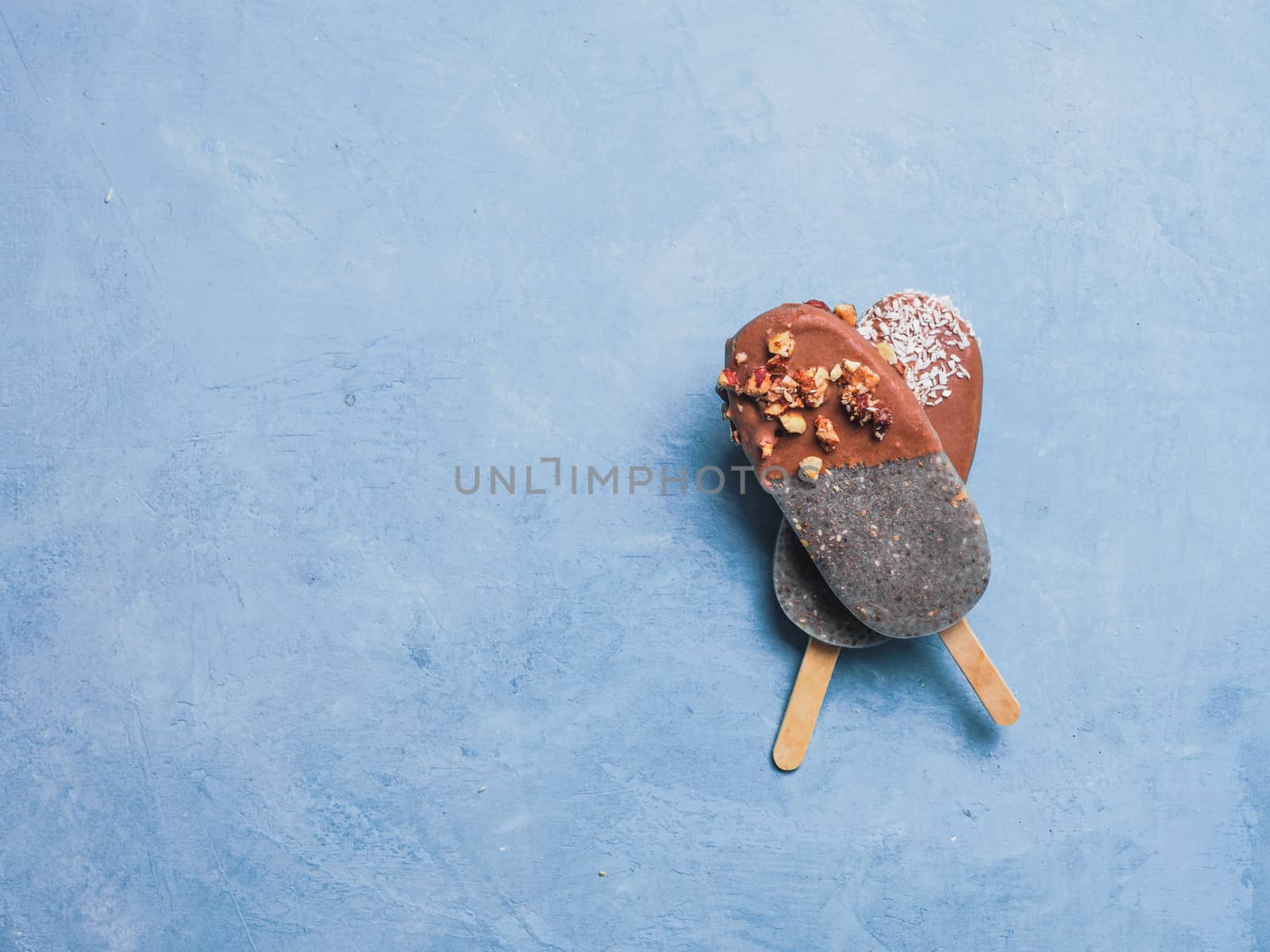Chia popsicle with chocolate on blue background. Healthy recipe and idea homemade vegan popsicle ice cream. Easter dessert idea. Copy space for text. Top view or flat-lay.