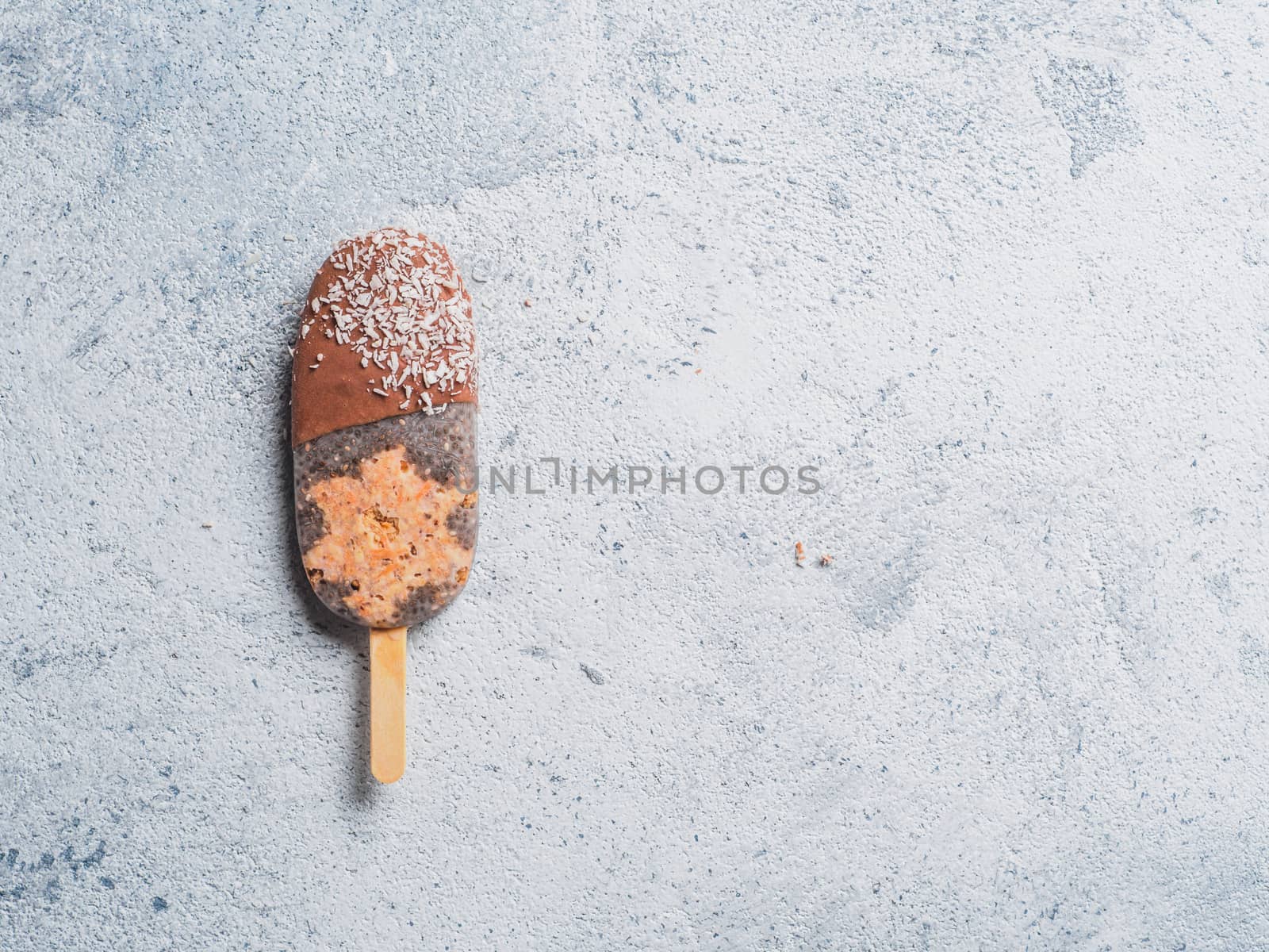 Chia popsicle with raw carrot cake and chocolate on gray background. Healthy recipe and idea homemade vegan popsicle ice cream. Easter dessert idea. Copy space for text. Top view or flat-lay.