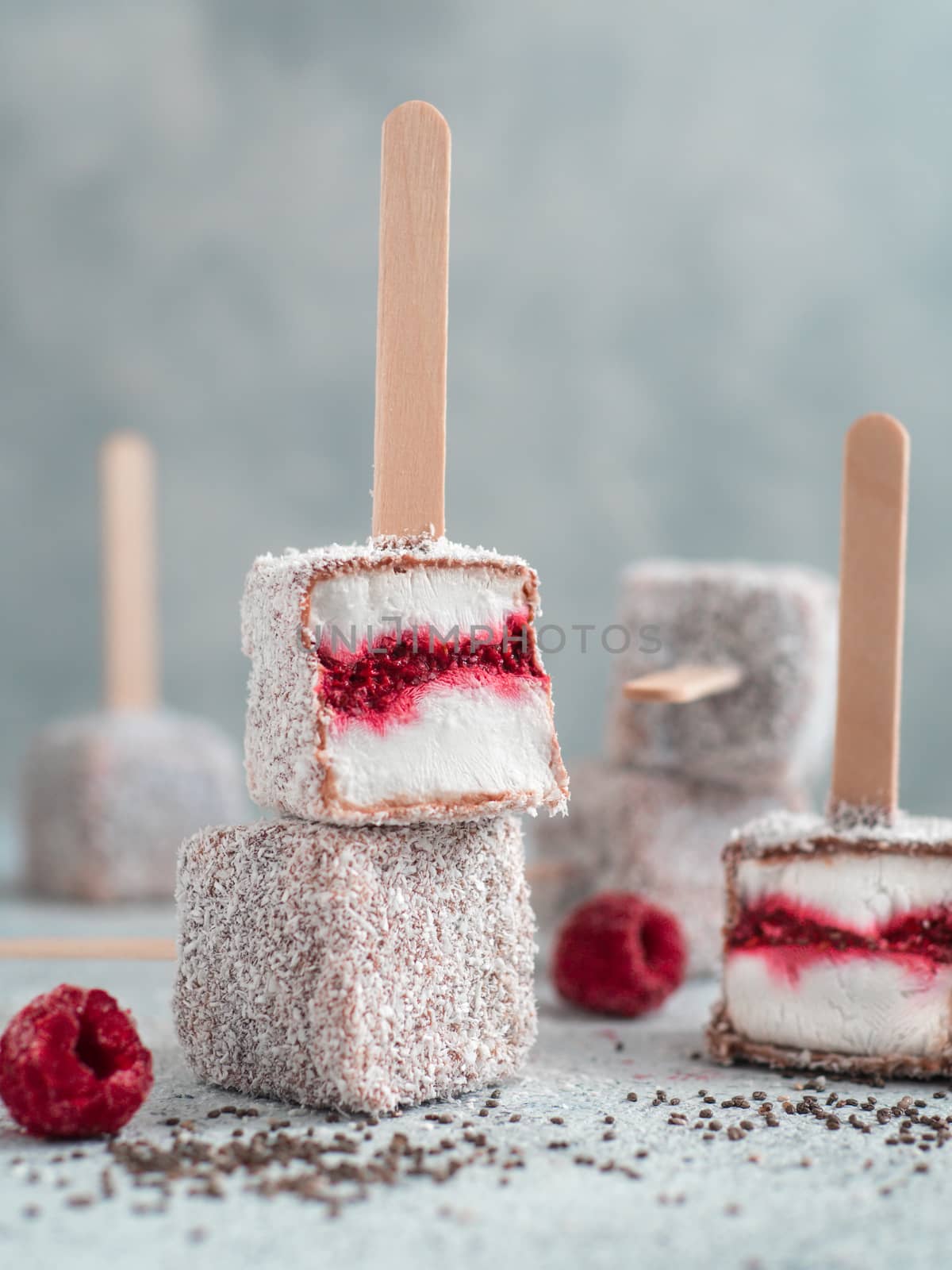 Homemade raw lamington ice cream pops on gray background. Australian sweet dessert lamington with chia and raspberries jam, chocolate and cocoa coat. Vegan food recipe and idea. Copy space for text