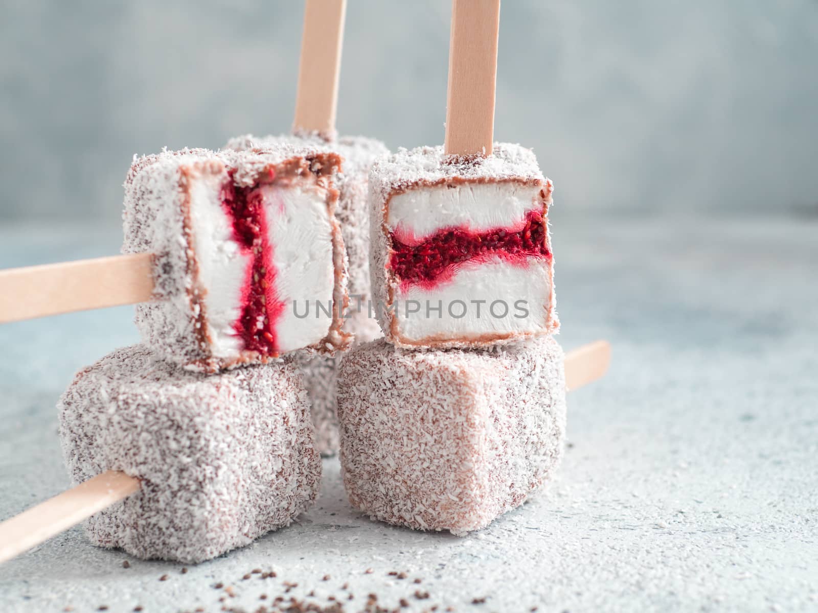 Homemade raw lamington ice cream pops on gray background. Australian sweet dessert lamington with chia and raspberries jam, chocolate and cocoa coat. Vegan food recipe and idea. Copy space for text