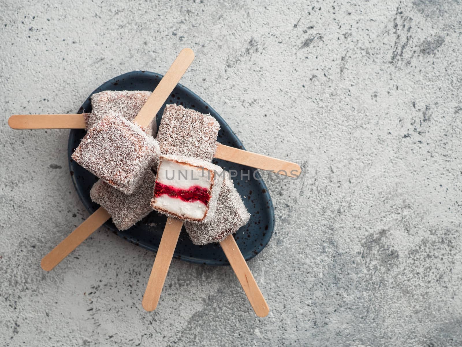 Homemade raw lamington ice cream pops on gray background. Australian sweet dessert lamington with chia and raspberries jam, chocolate and cocoa coat. Vegan food recipe and idea. Copy space. Top view