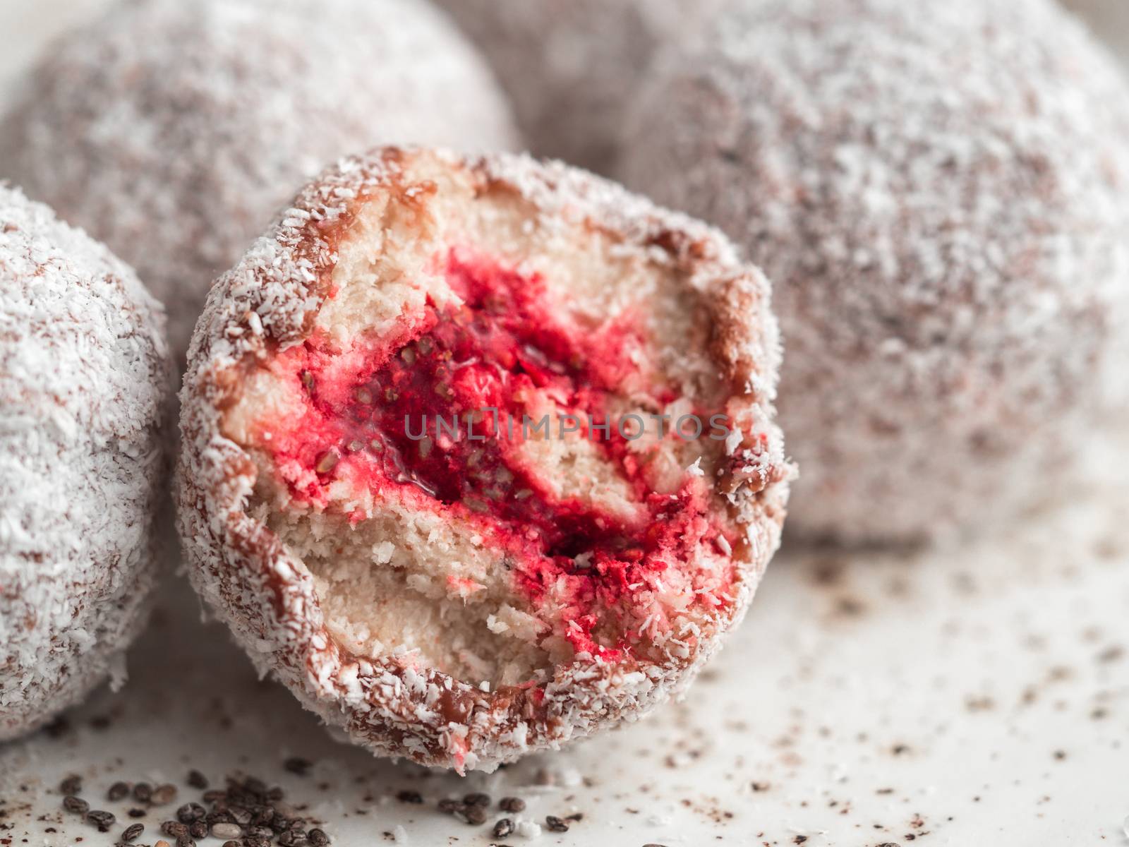 Raw vegan lamington bliss balls with raspberries chia jam on gray background. No baked healthy vegan sweet dessert idea and recipe. Close up