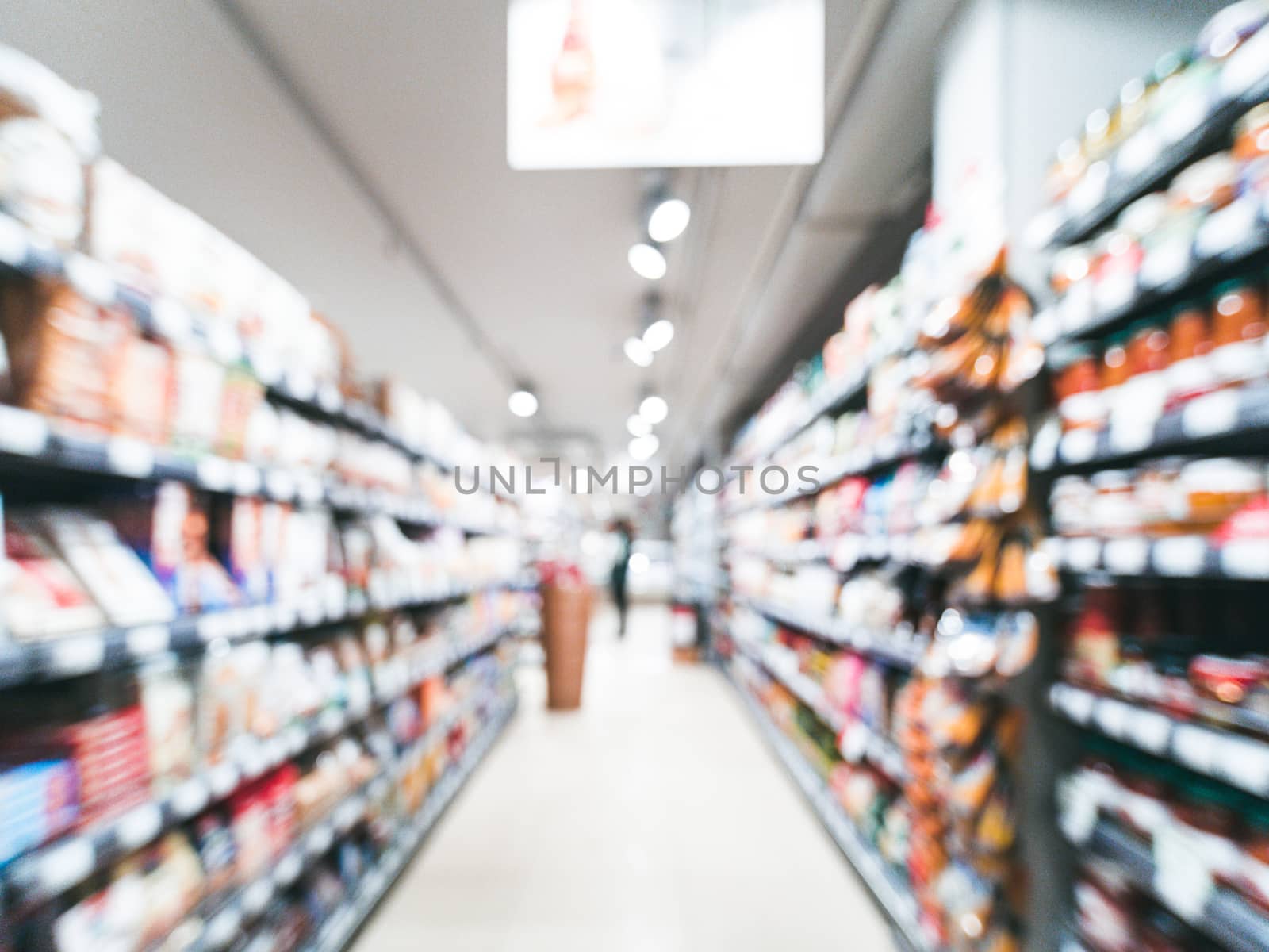 Abstract blurred supermarket aisle with colorful shelves and unrecognizable customers as background
