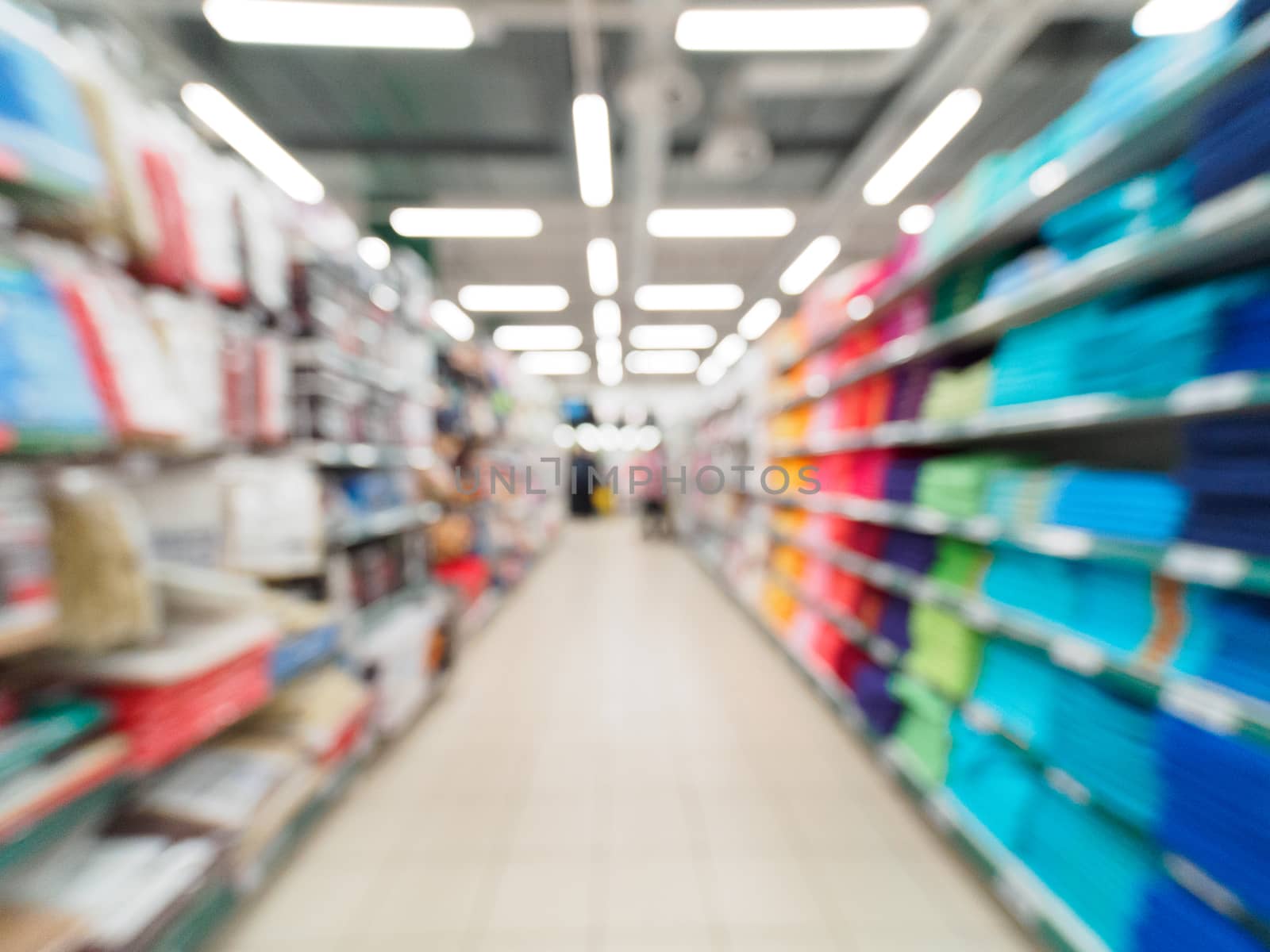 Abstract blurred supermarket aisle with colorful shelves and unrecognizable customers as background