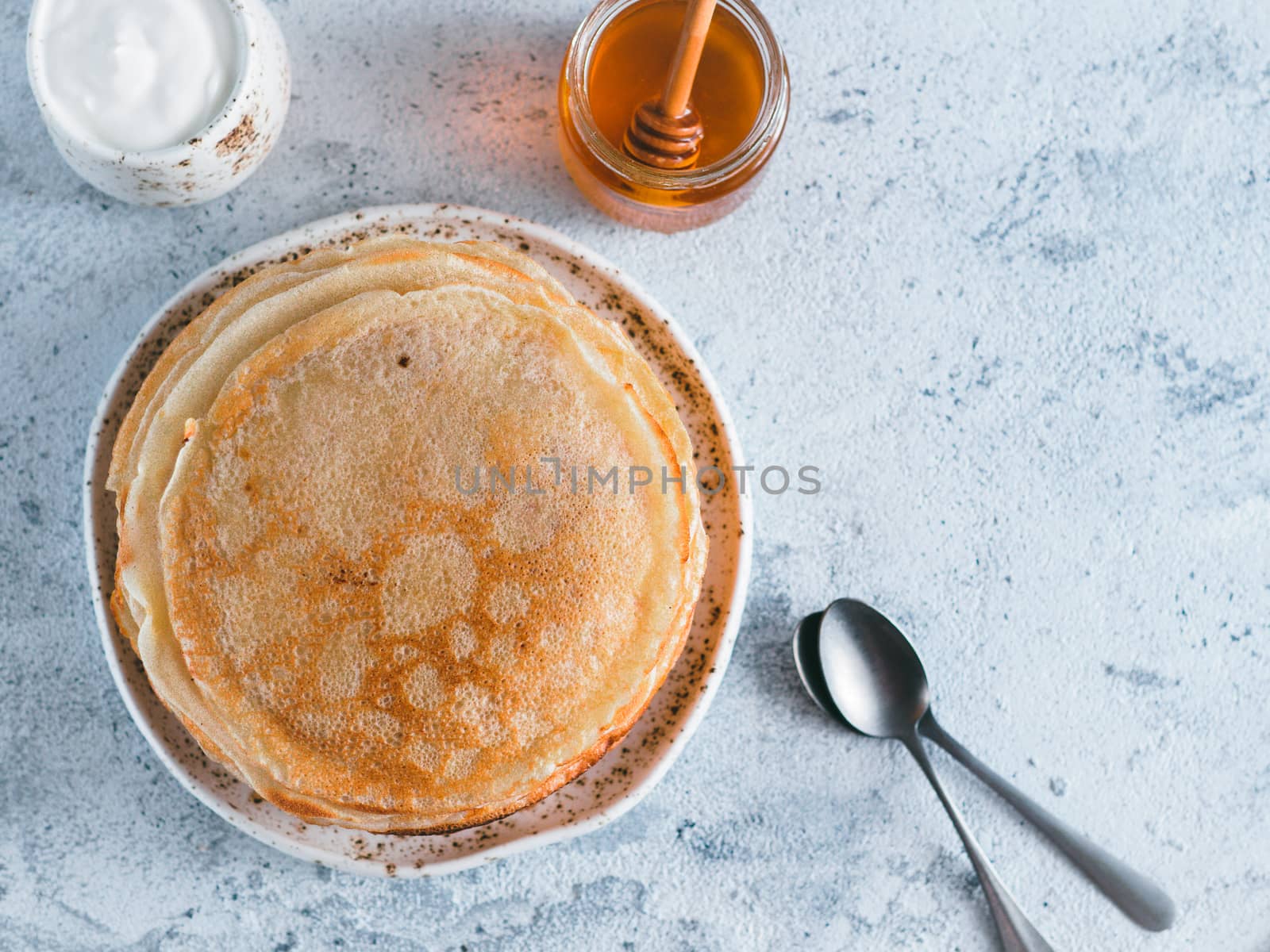 Stack of traditional russian pancakes blini on gray background with copy space. Homemade russian thin pancakes blini. Russian food, russian kitchen. Top view or flat lay