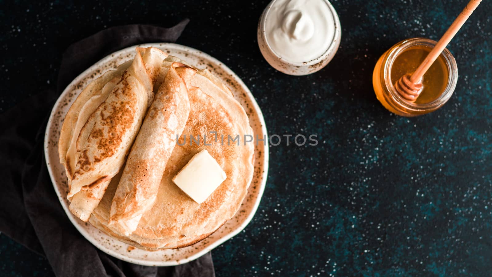 Stack of traditional russian pancakes blini on black background with copy space. Homemade russian thin pancakes blini. Russian food, russian kitchen. Top view or flat lay