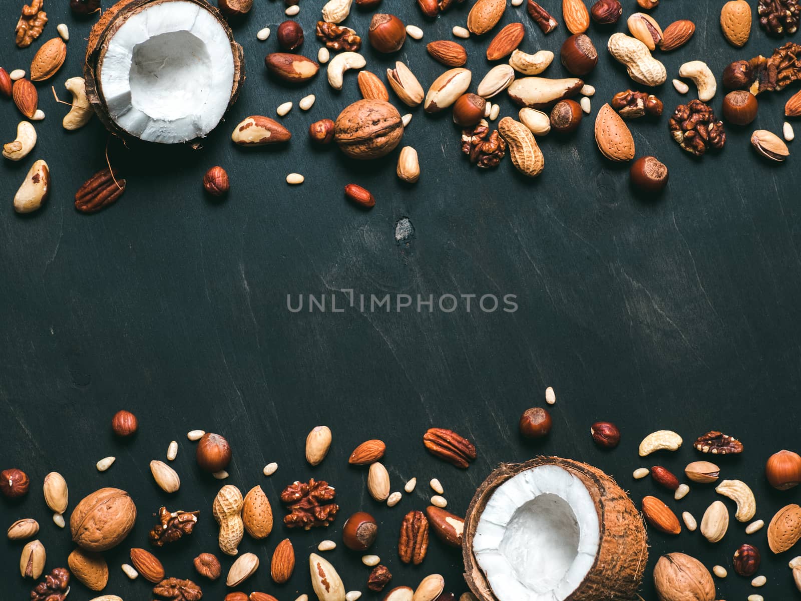 Background of mixed nuts - coconut, hazelnuts, walnuts, almonds, pecan, pistachio, brazil nut, pine nuts, peanut - on dark background. Copy space. Top view or flat lay