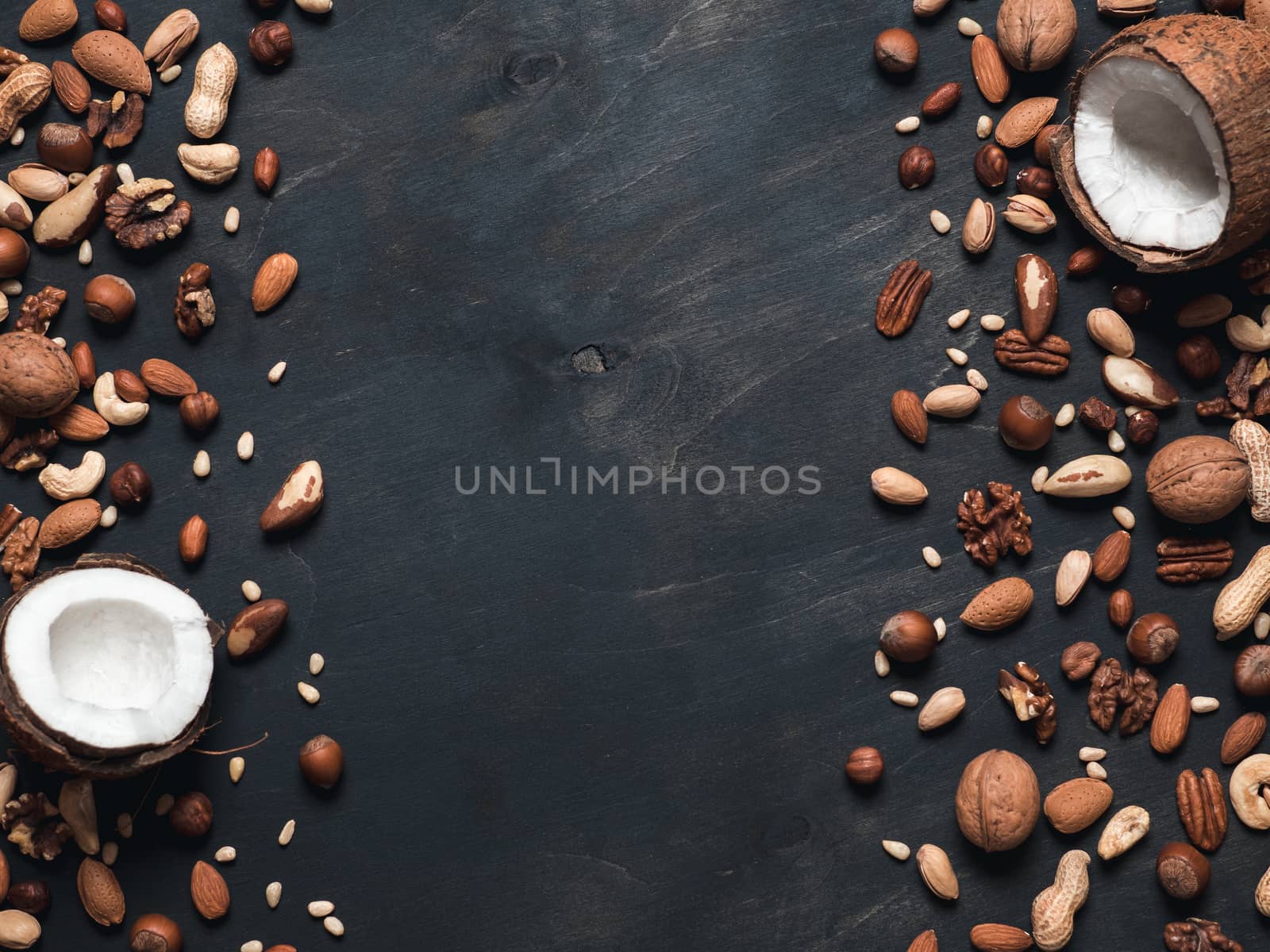 Background of mixed nuts - coconut, hazelnuts, walnuts, almonds, pecan, pistachio, brazil nut, pine nuts, peanut - on dark background. Copy space. Top view or flat lay