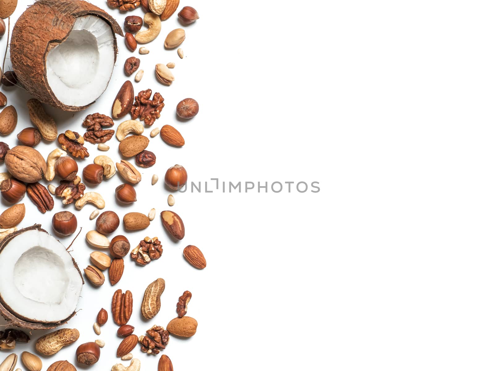 Background of mixed nuts - coconut, hazelnuts, walnuts, almonds, pecan, pistachio, brazil nut, pine nuts, peanut - with copy space. Isolated one edge. Top view or flat lay