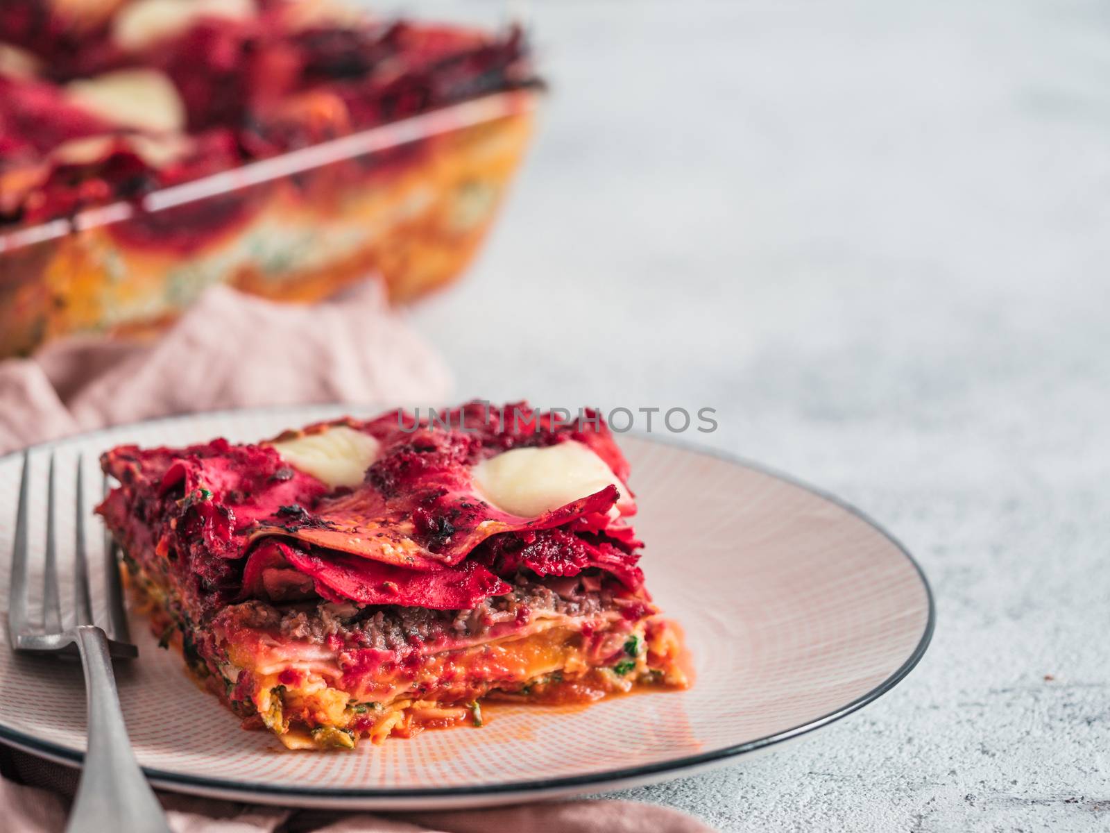 Vegetable Packed Rainbow Lasagne on pink plate. Ideas and recipes for healthy vegetarian dinner or lunch. Lasagne with beetroot, pumpkin, mushrooms, ricotta, spinach, mozarella. Copy space for text.