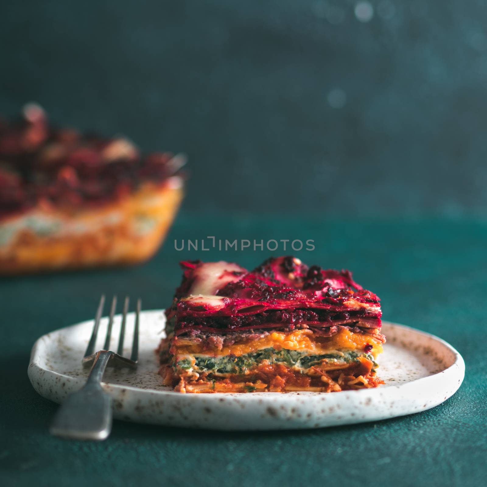 Vegetable Packed Rainbow lasagne on green background.Ideas and recipes for healthy vegetarian dinner or lunch.Lasagne with beetroot, pumpkin, mushrooms, ricotta, spinach, mozarella.Copy space for text