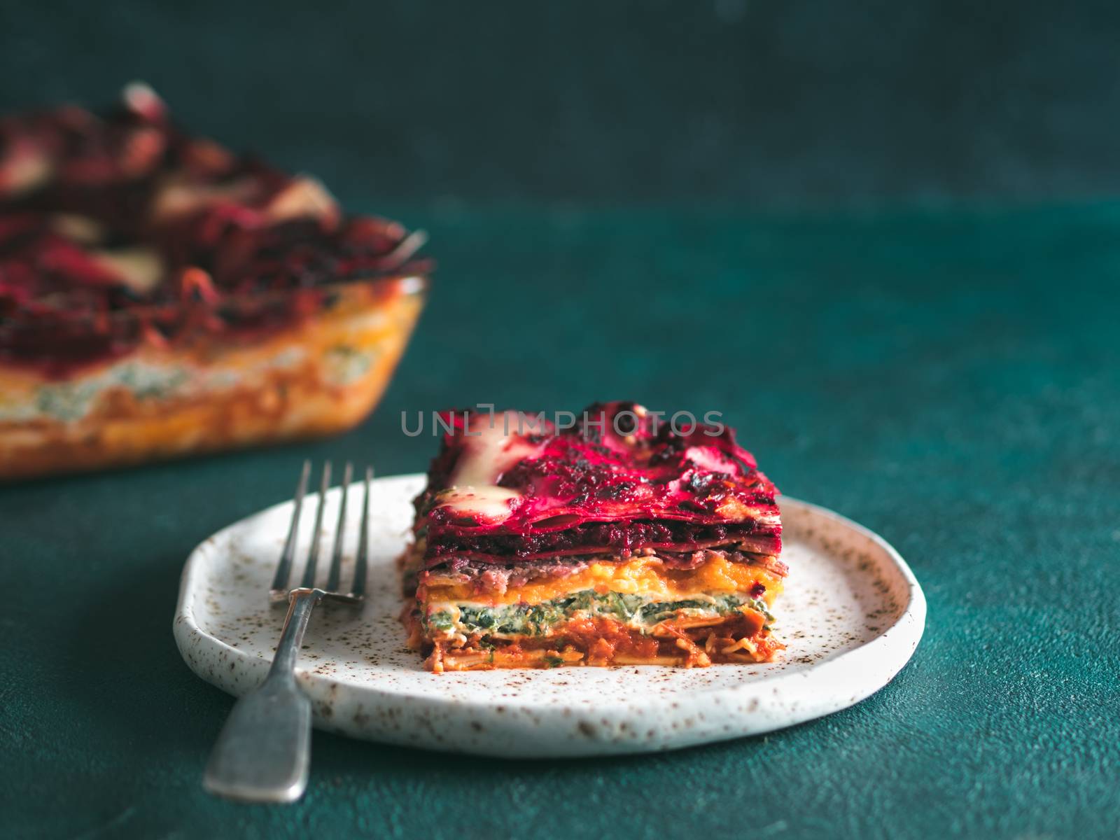 Vegetable Packed Rainbow lasagne on green background.Ideas and recipes for healthy vegetarian dinner or lunch.Lasagne with beetroot, pumpkin, mushrooms, ricotta, spinach, mozarella.Copy space for text