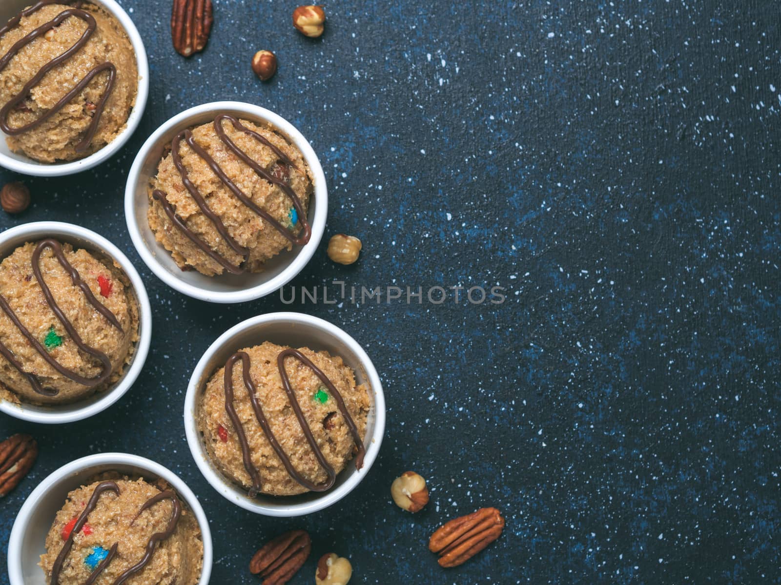 Safe-to-eat raw monster cookie dough in small portion bowl on dark blue background. Ideas and recipes for kids and toddlers meal. Top view or flat-lay. Copy space for text.