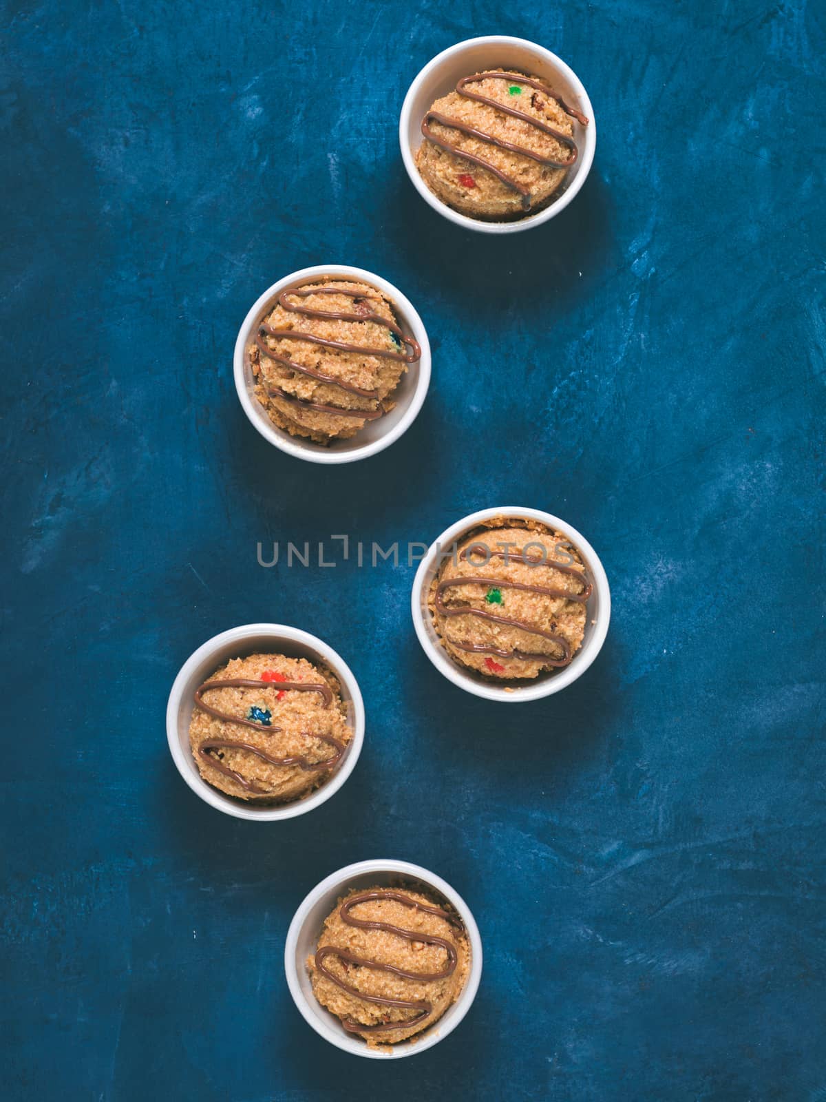 Safe-to-eat raw monster cookie dough in small portion bowl on blue background. Ideas and recipes for kids and toddlers meal. Top view or flat-lay. Copy space for text.