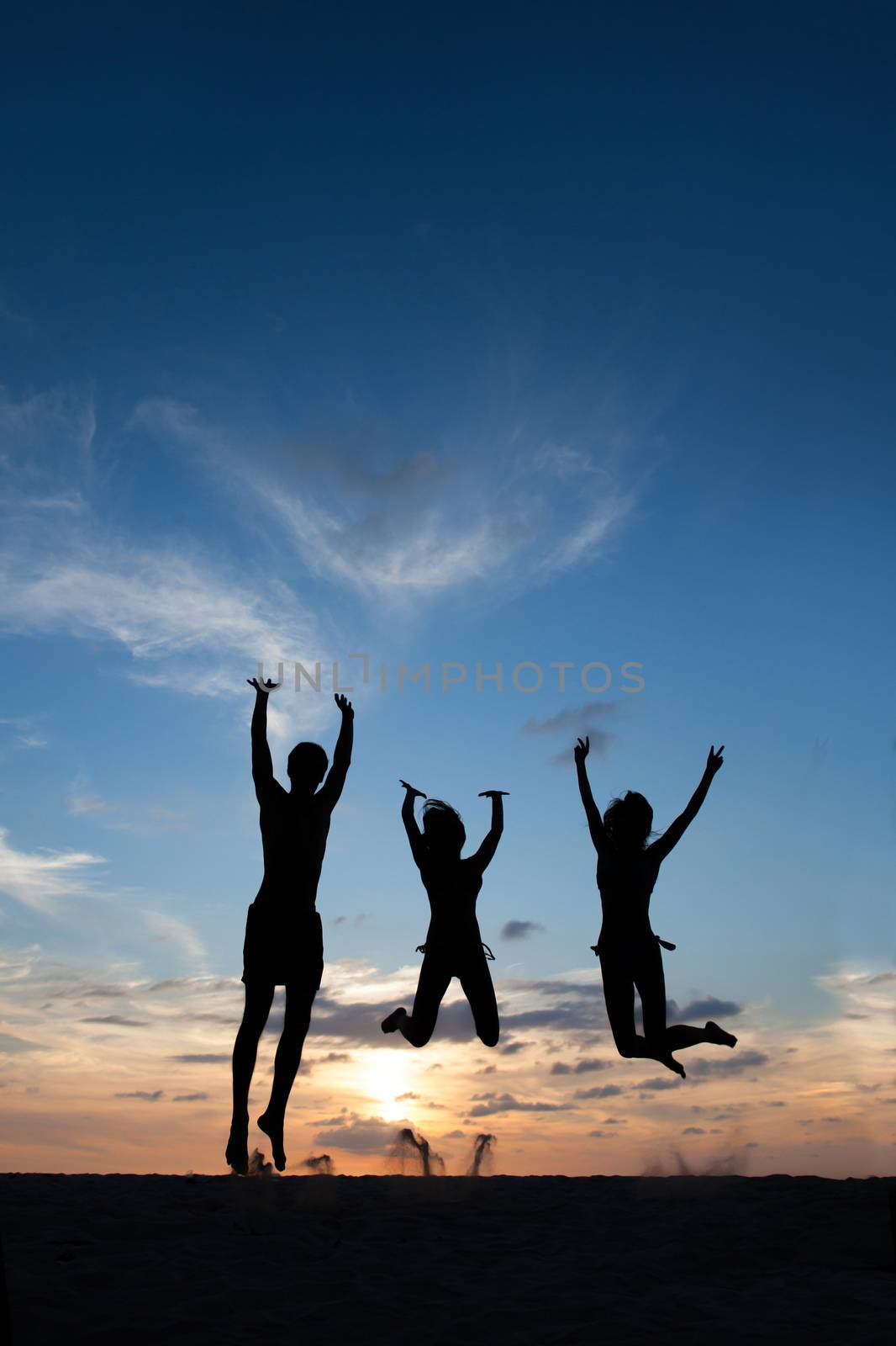 Happy female friends having fun on beach at sunset