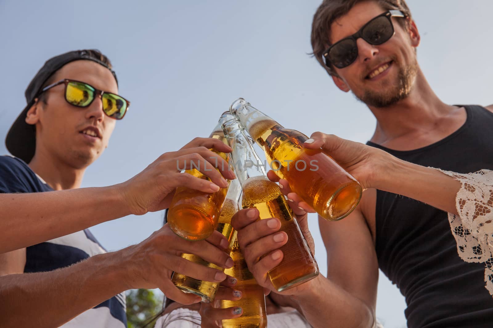 Happy young friends drinking beer outdoors