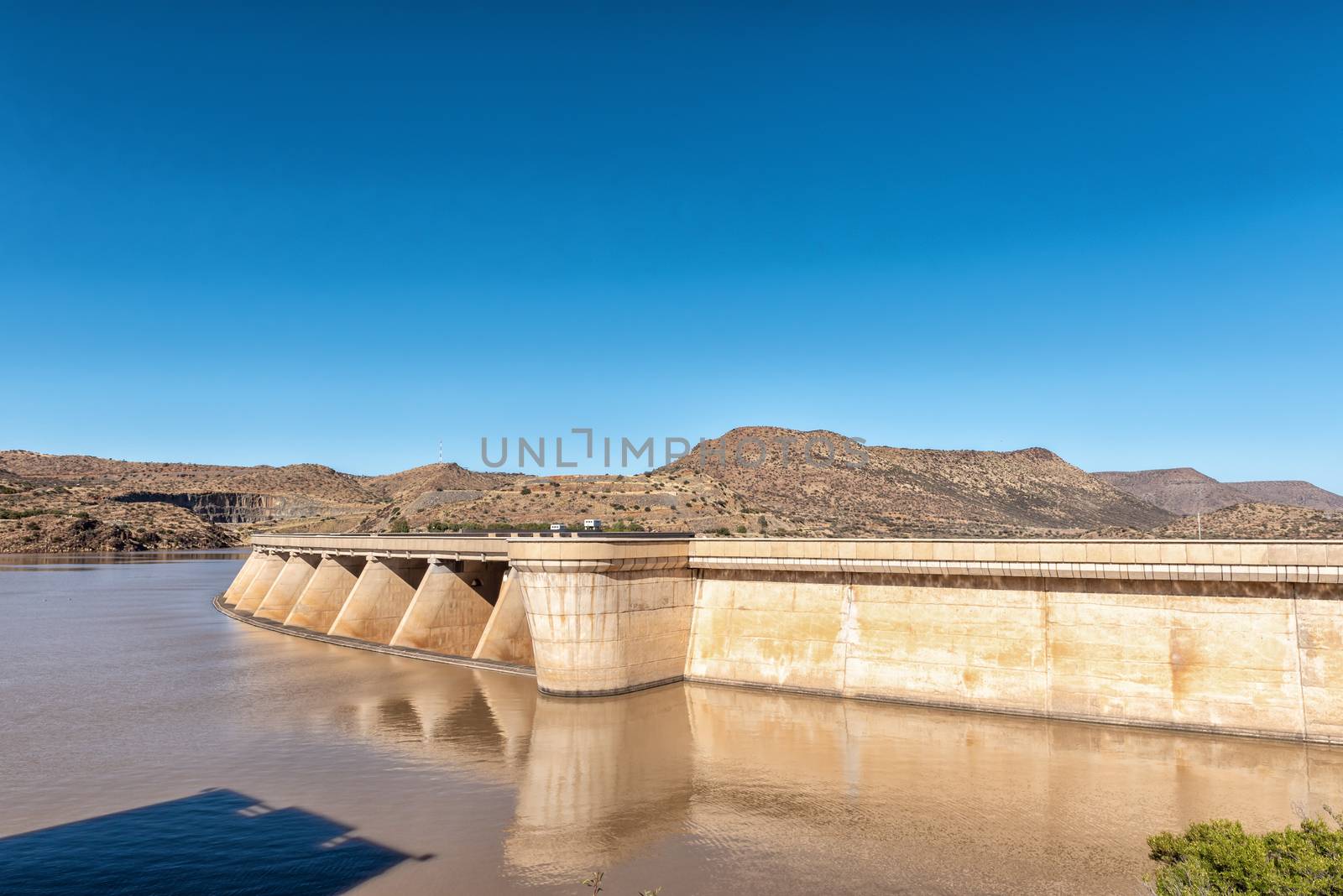 Wall of the Vanderkloof Dam in the Orange River. The road to the Vanderkloof town in the Northern Cape Province is visible on the hills in the back