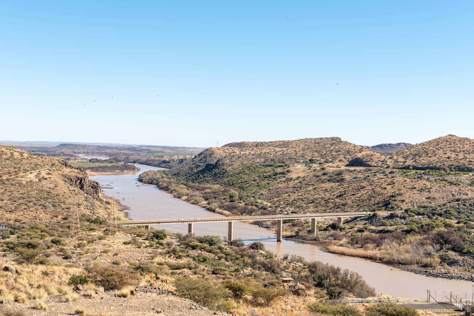 View downstream from the wall of the Vanderkloof Dam in the Orange River. The The river and single lane road bridge are visible