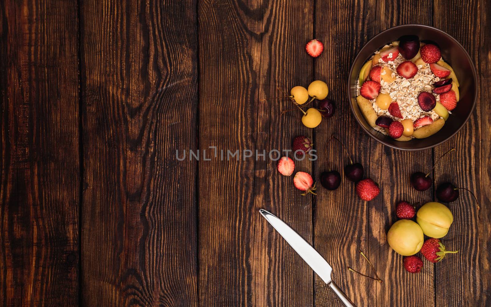 Breakfast with porridge, fruits and berries on weathered wooden textured table on background or old panels with cracks, scratches, swirls