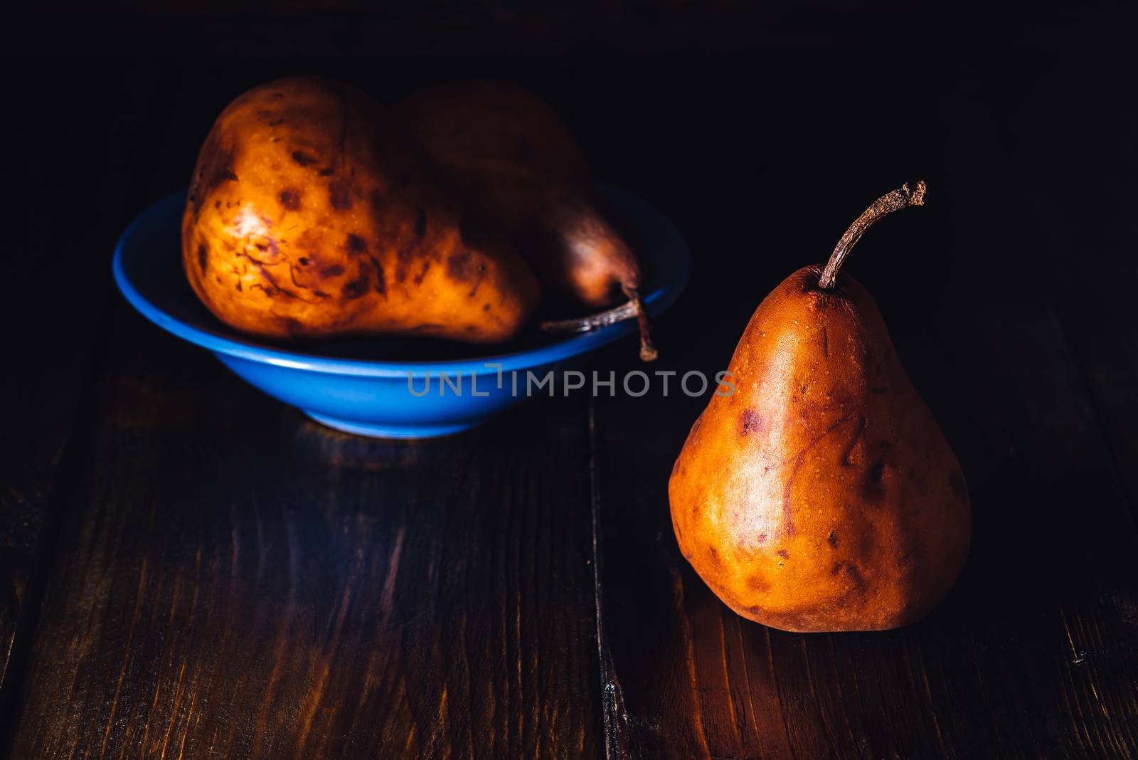 Golden Pears in Blue Bowl and One Pear Near.