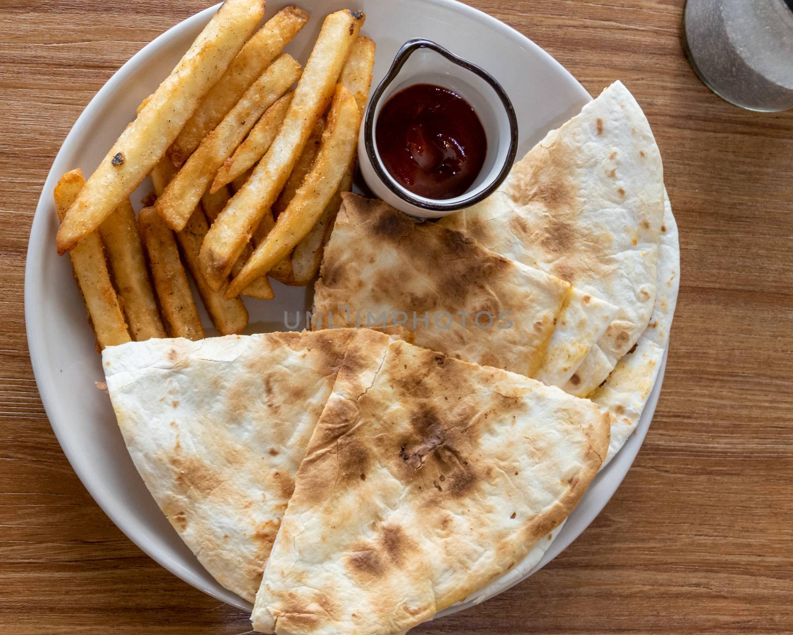 Quesadilla and french fries on plate, shot from above