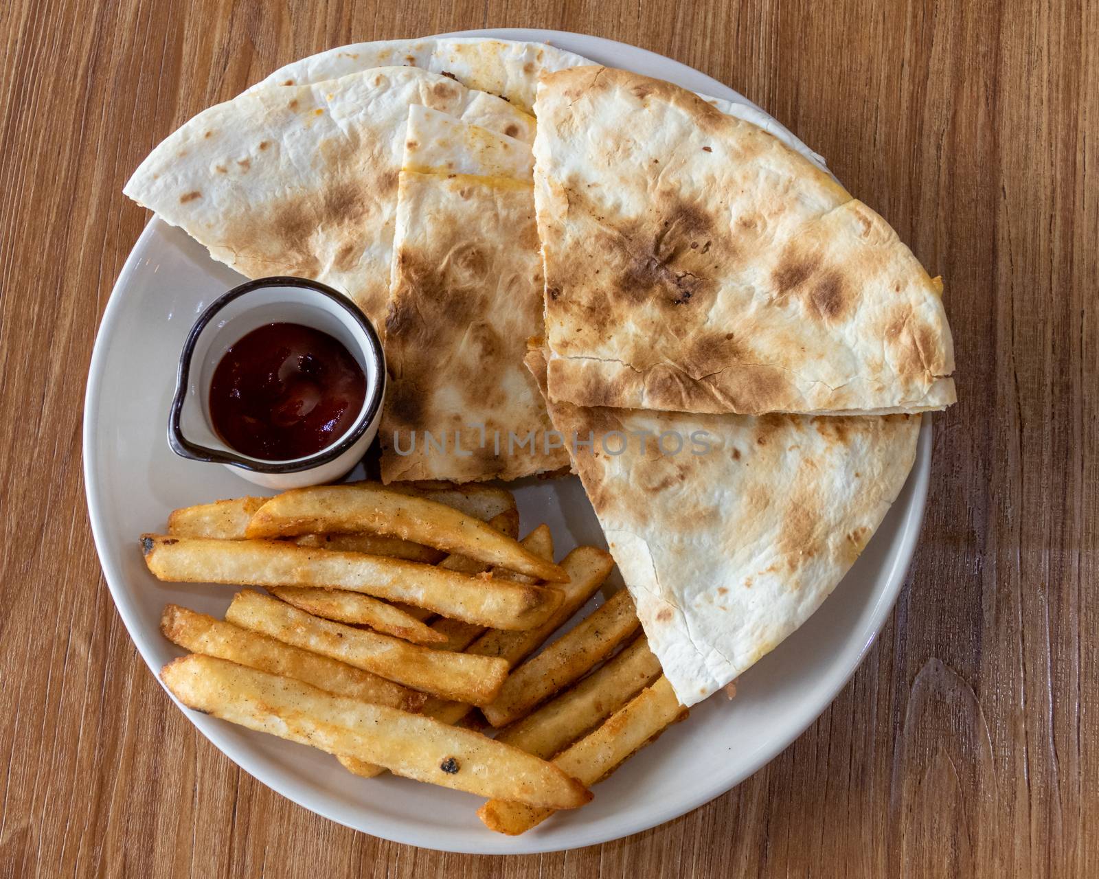 Quesadilla and french fries on plate, shot from above