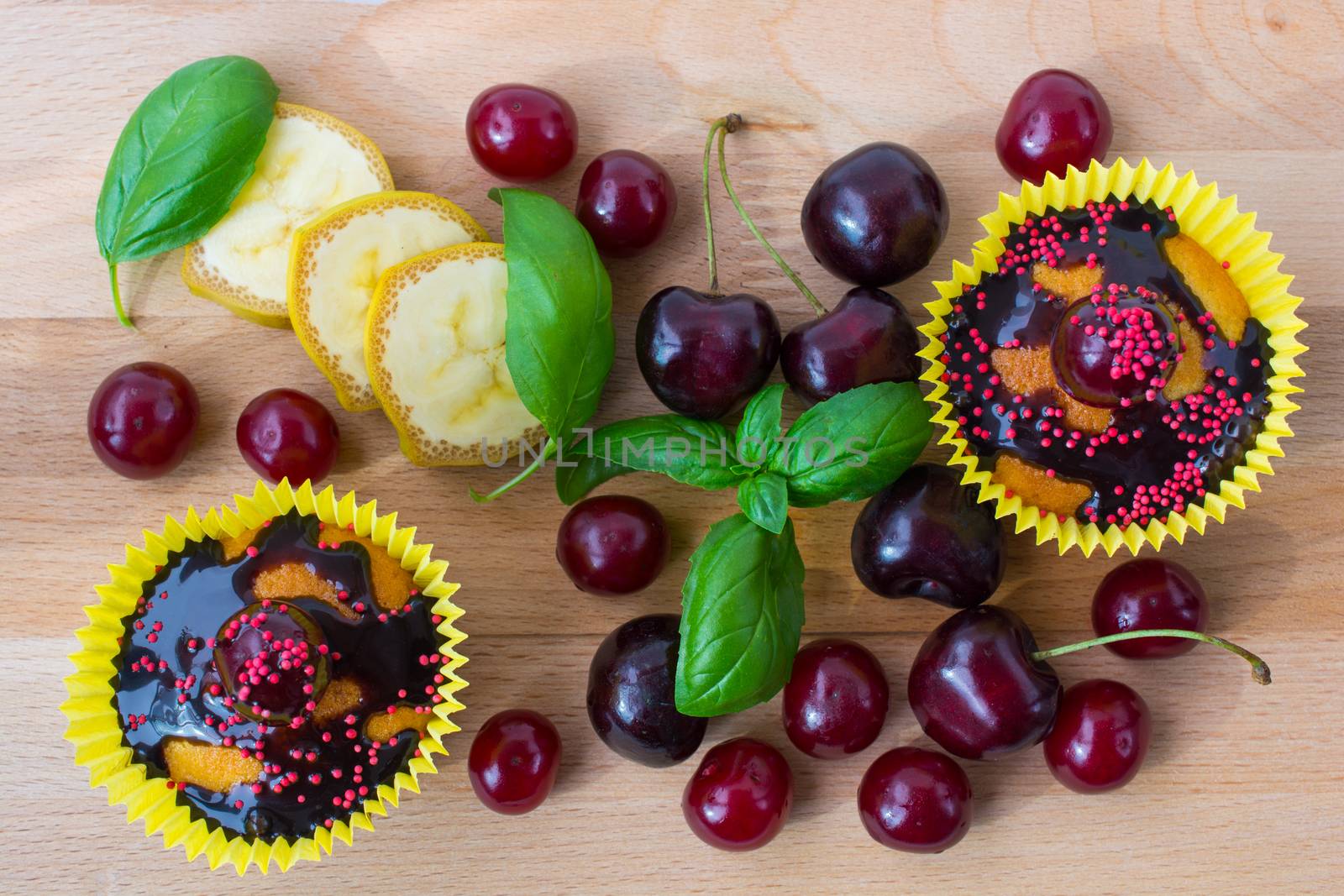 Delicious homemade cupcakes isolated on a wooden background with cherry, confectionery and chocolate sauce. served with fruit pieces. Top view.