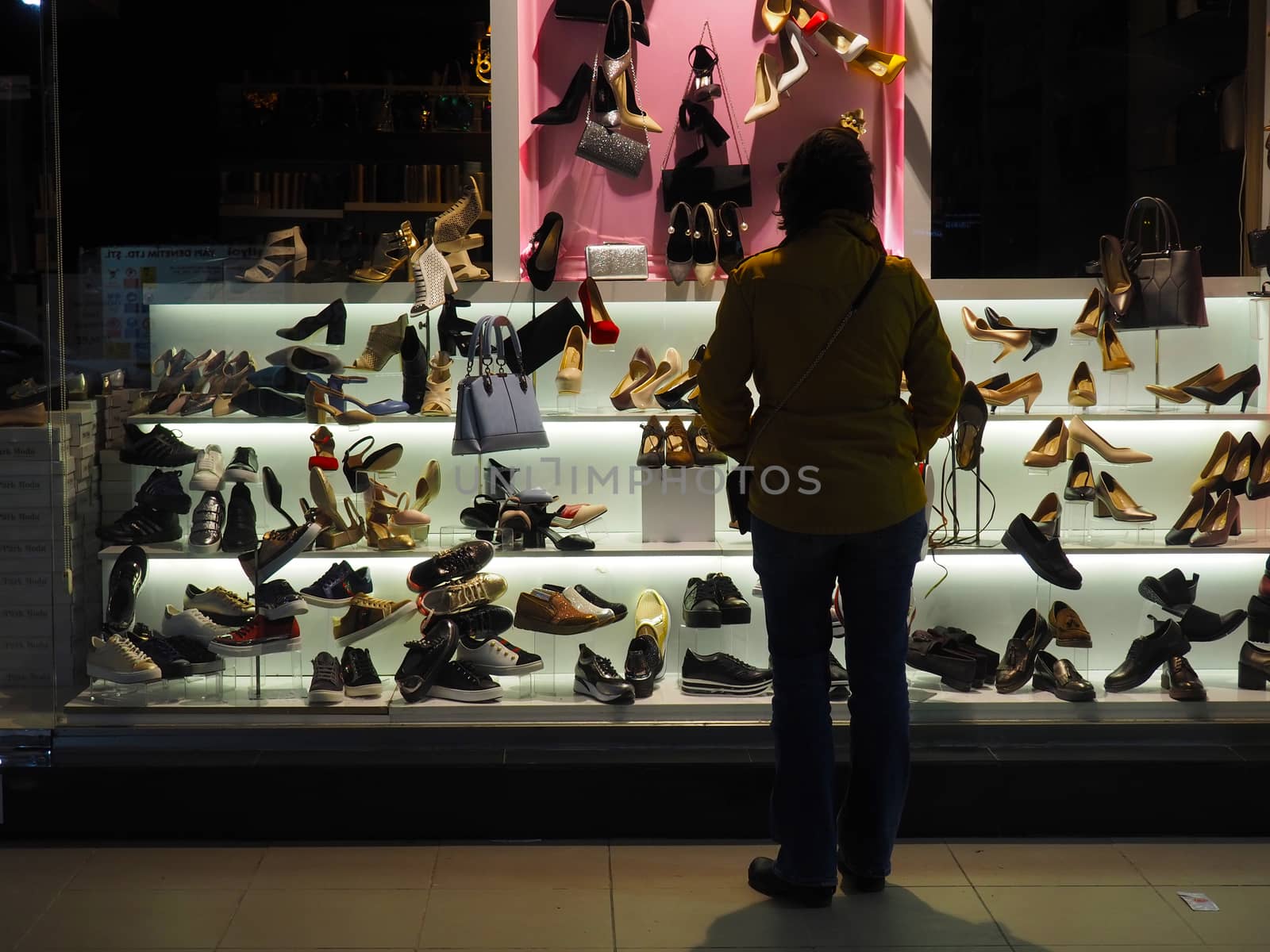 night shopping. the beautiful woman who watches the shoe shop display case
