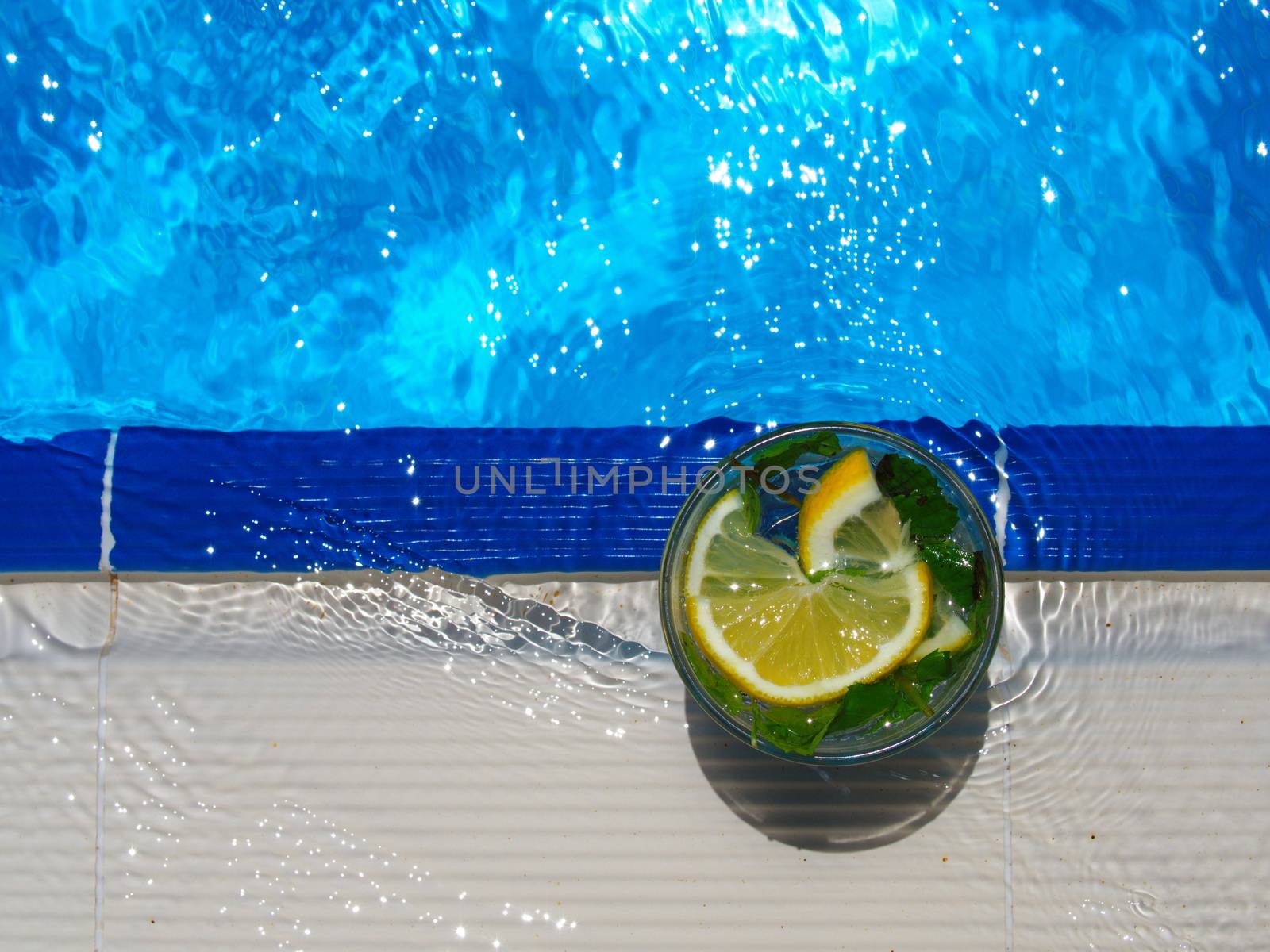 enjoying fresh lemon and mint mojito cocktail by the pool