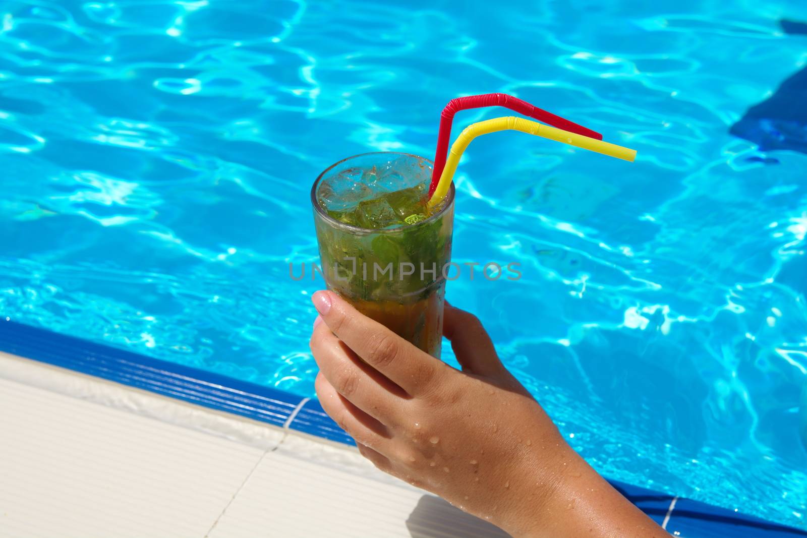 enjoying fresh lemon and mint mojito cocktail by the pool