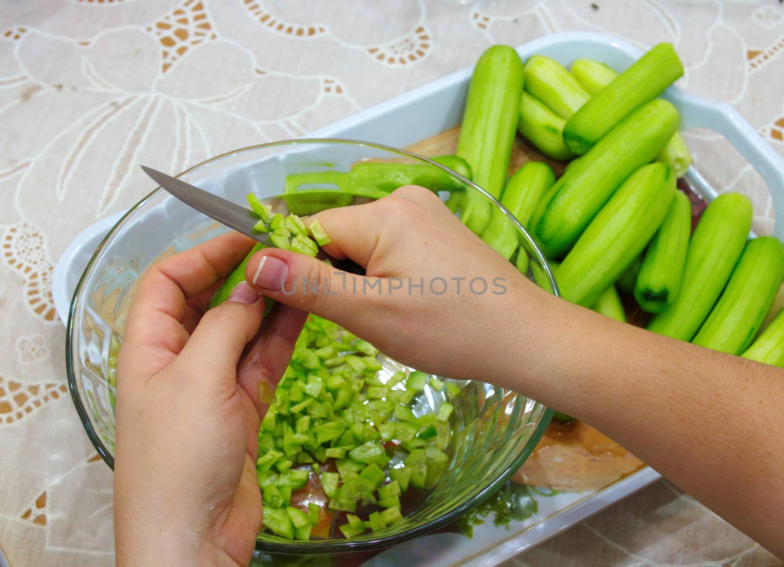 prepare a salad. cleanses cucumber shells with women's hands. cucumber is cleaned with a peeling knife. Preparing for meals