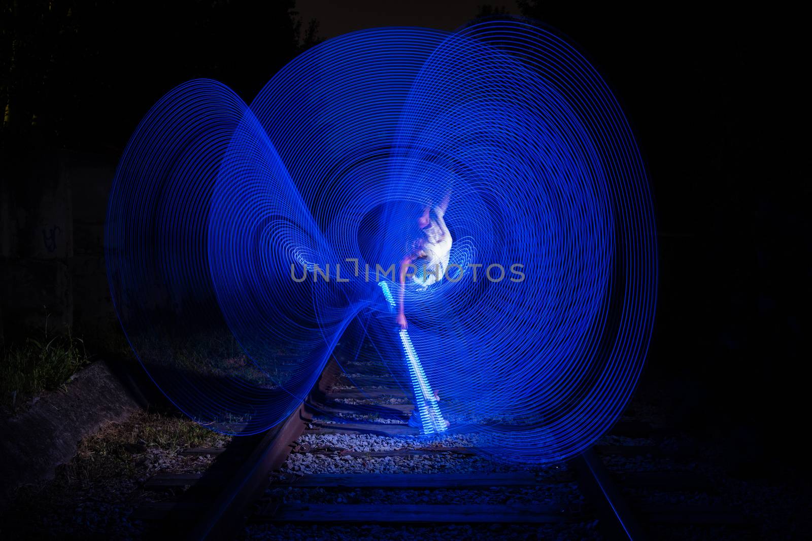 Young girl surrounded by frozen light. Drawing with light. Long exposure. Artistic abstraction. Freezelight.