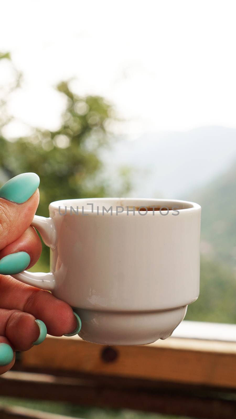 Hand white cup of hot coffee. In the morning, cold mountain views, soft focus, blurred