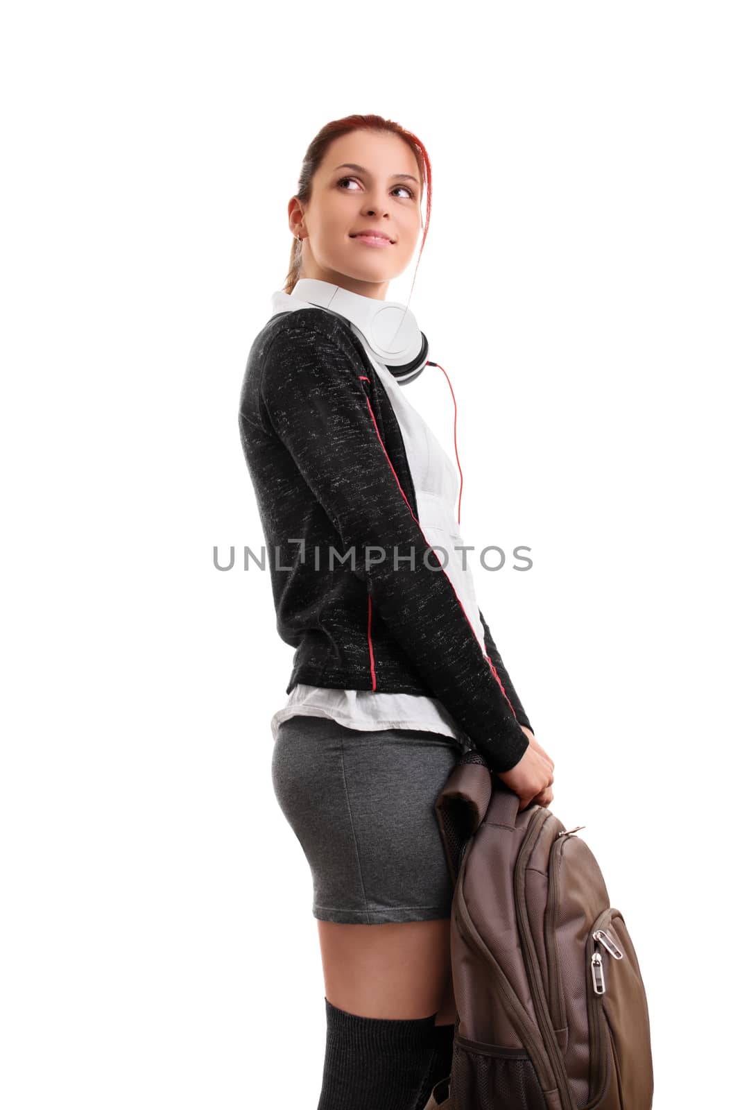 A portrait of a smiling female student in uniform with headphones, holding a backpack, isolated on white background. I can't wait to go back to school.