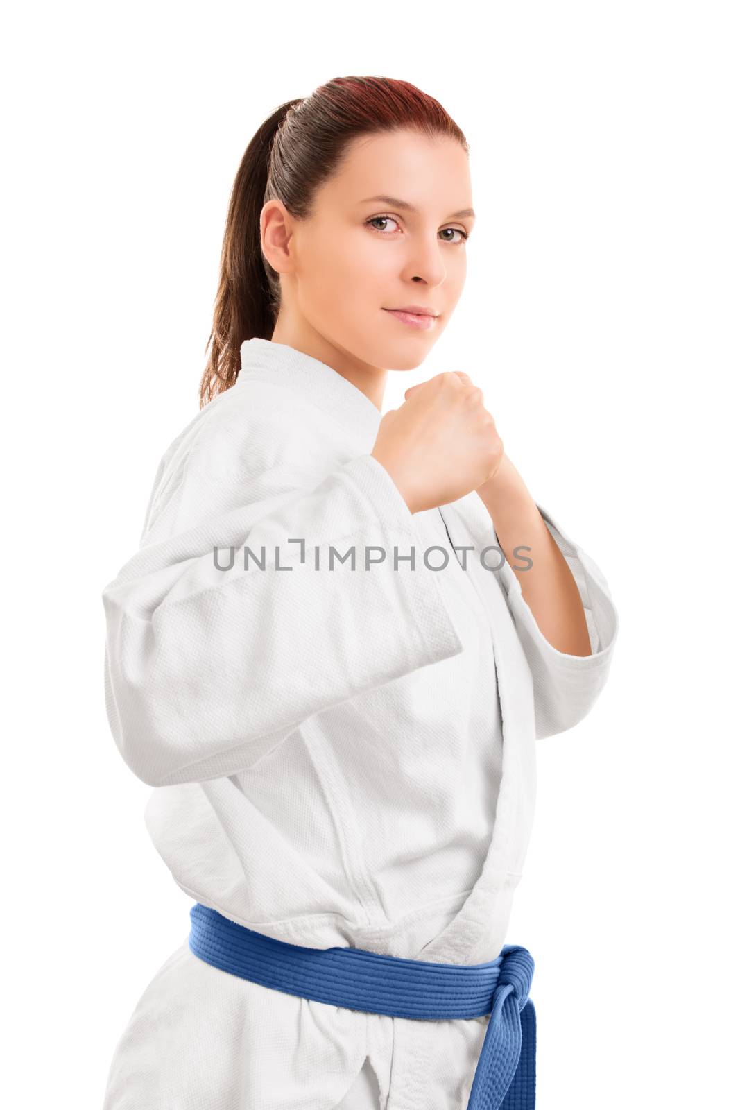 A portrait of a beautiful young girl in a kimono with blue belt standing in a combat stance, isolated on white background.
