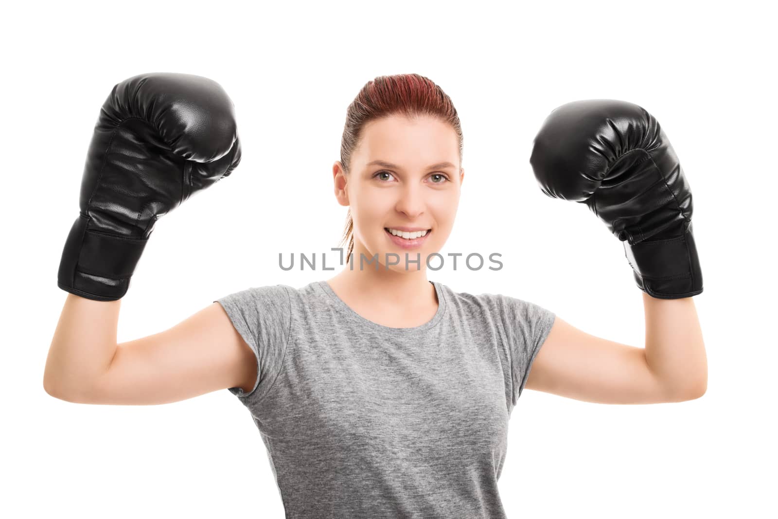 A portrait of a young beautiful girl with boxing gloves cheering, celebrating her success, isolated on white background.