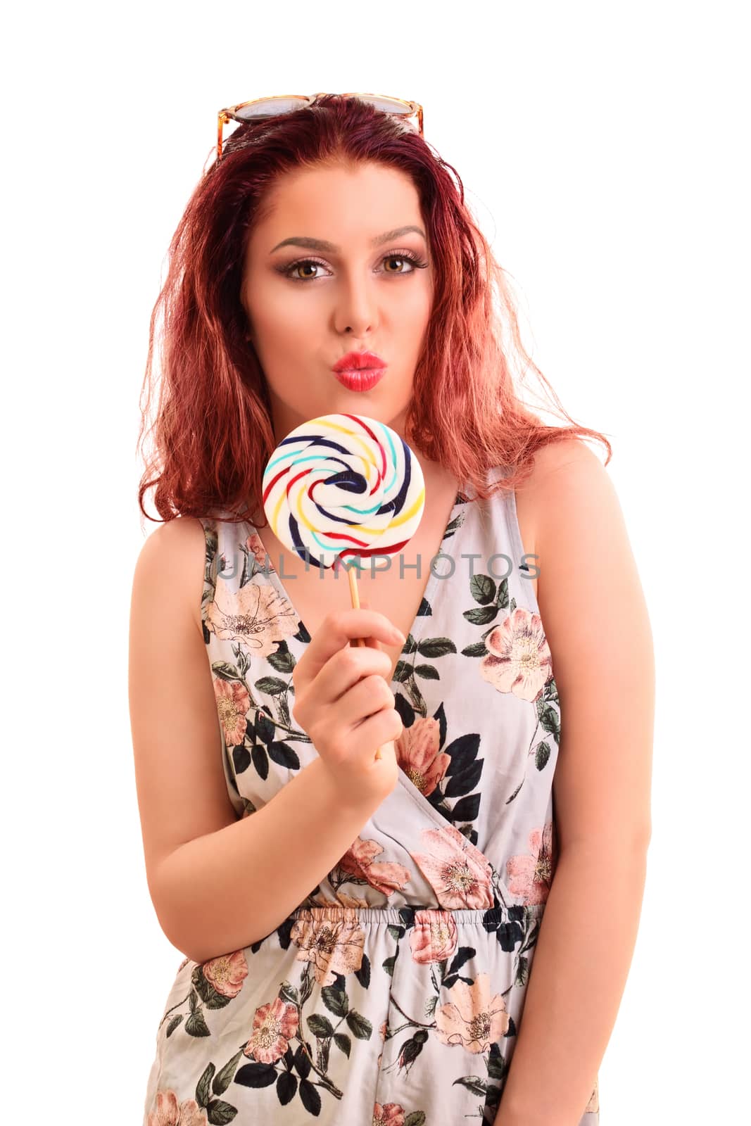 Portrait of a beautiful young girl holding a lollipop, sending a kiss, isolated on white background.