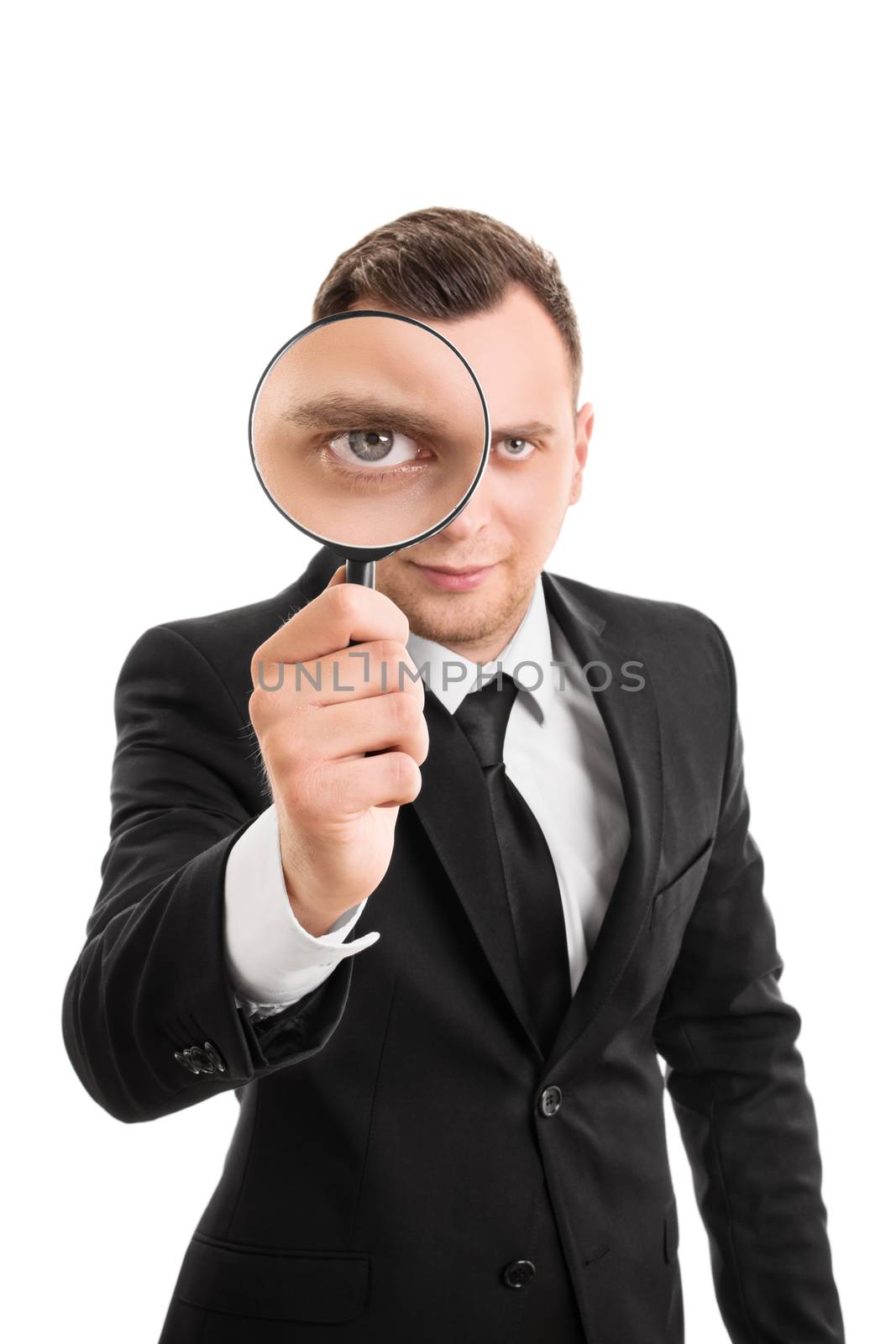 A portrait of a young businessman looking through a magnifying glass, isolated on white background.