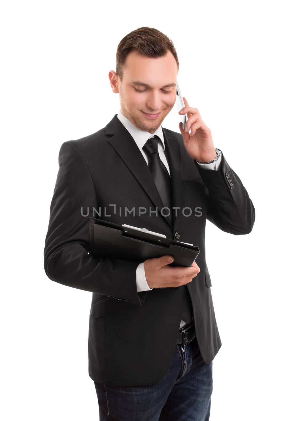 Portrait of a young businessman, holding a notepad, talking on a phone isolated on white background.