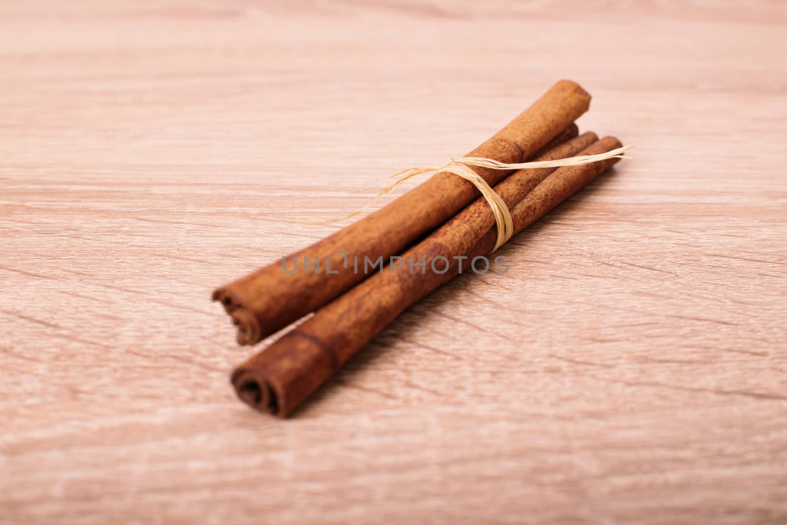 Heap of cinnamon sticks on a textured wooden background.
