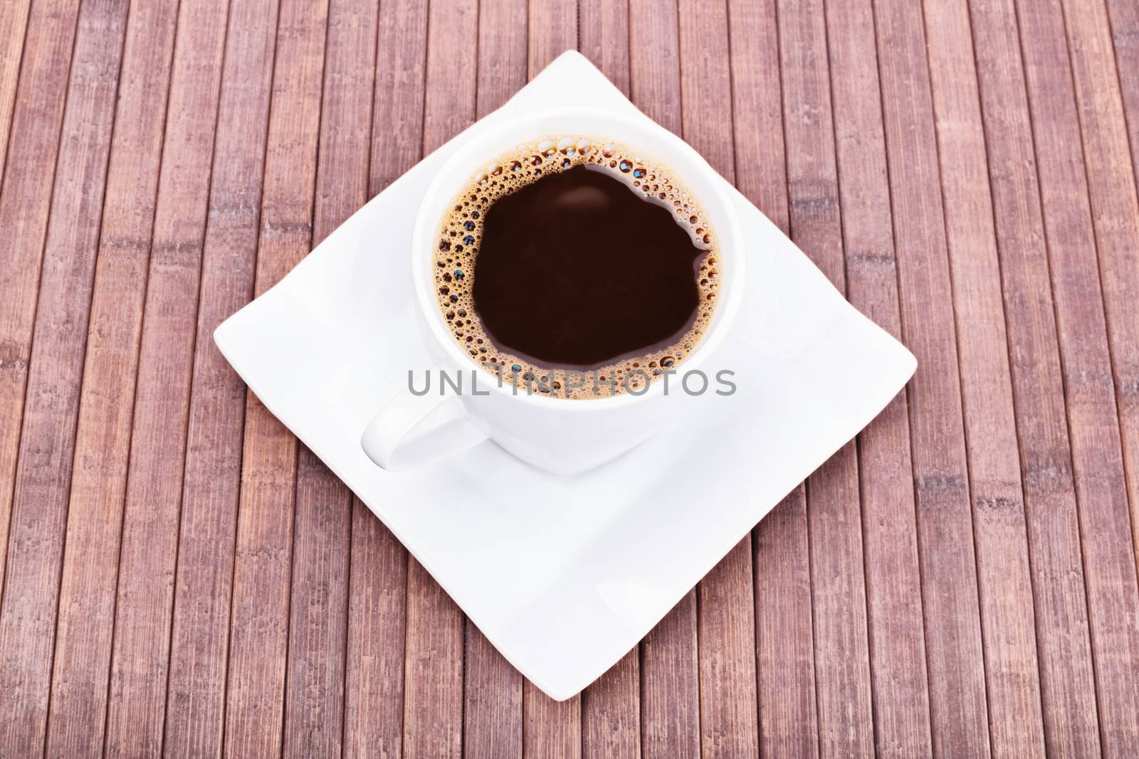 White cup of freshly brewed coffee on wooden background.