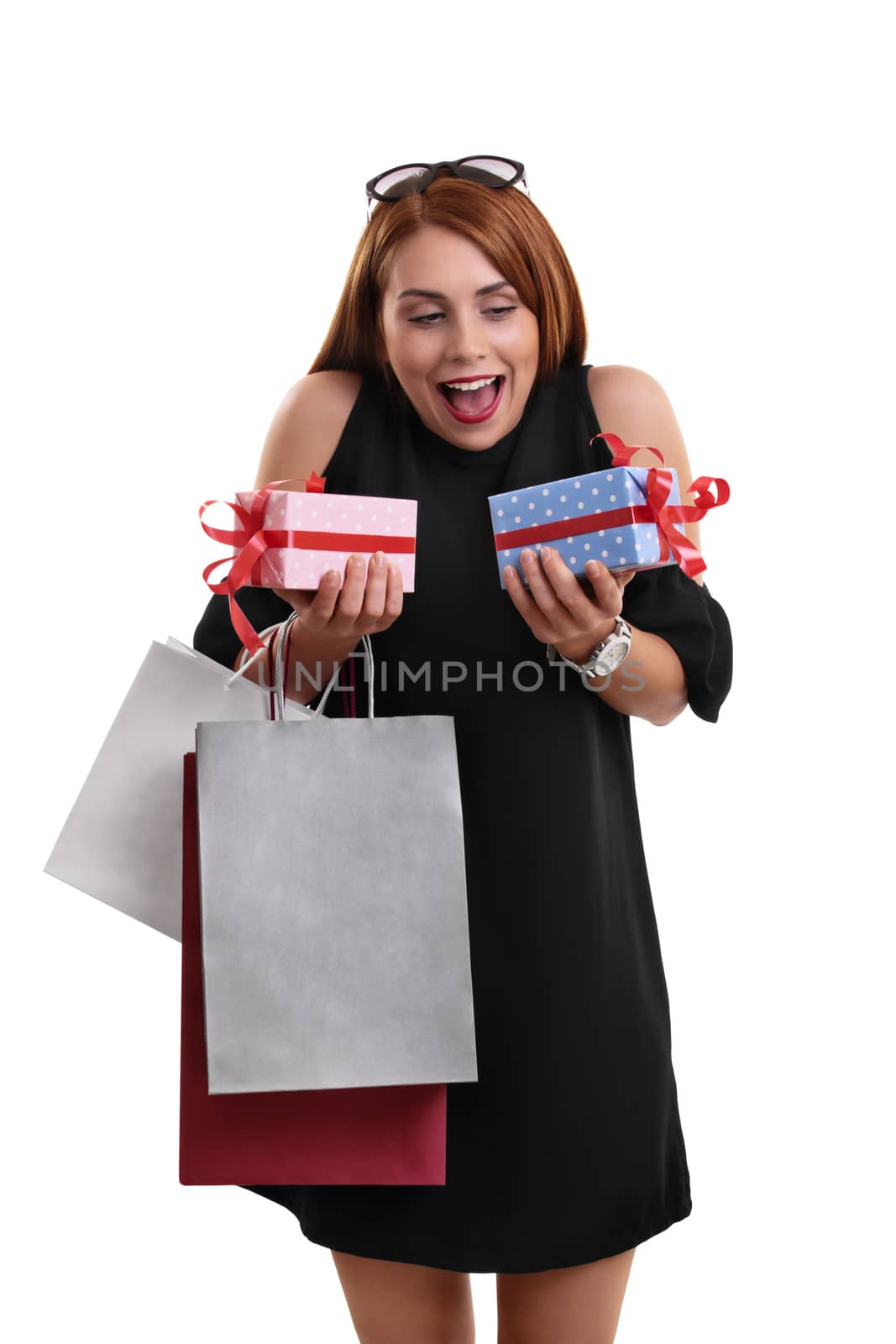 Excited beautiful young woman in a black dress holding shopping bags and presents, isolated on a white background.