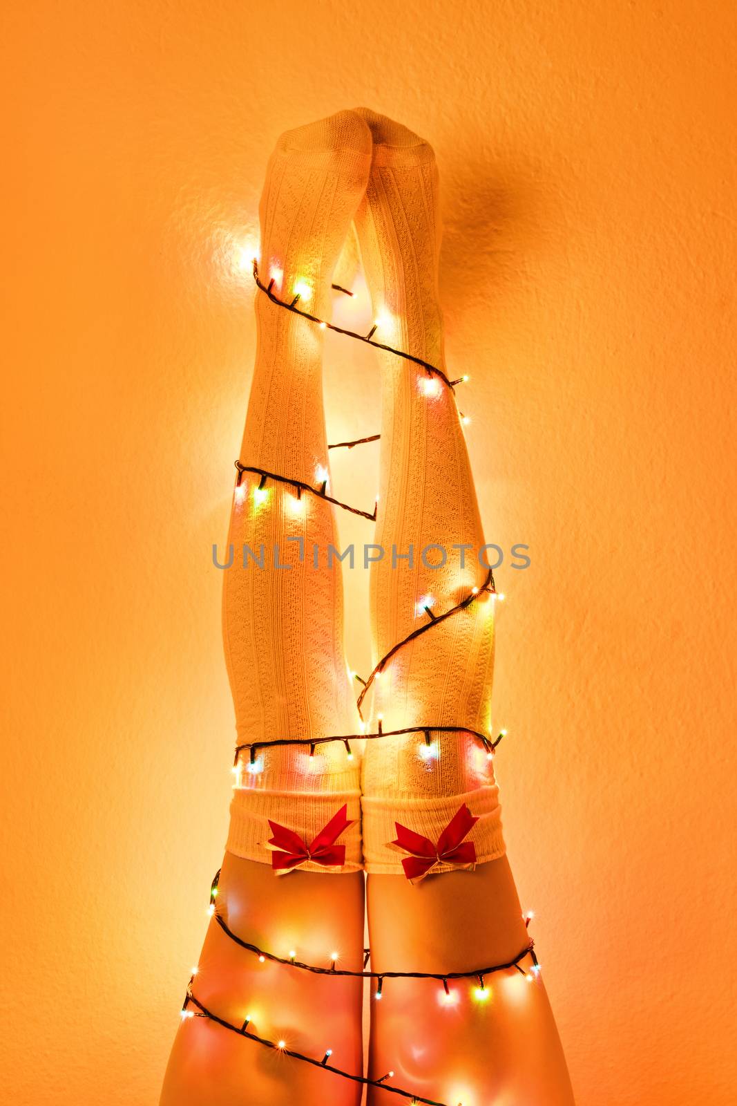 Female legs wrapped with christmas tree lights by Mendelex