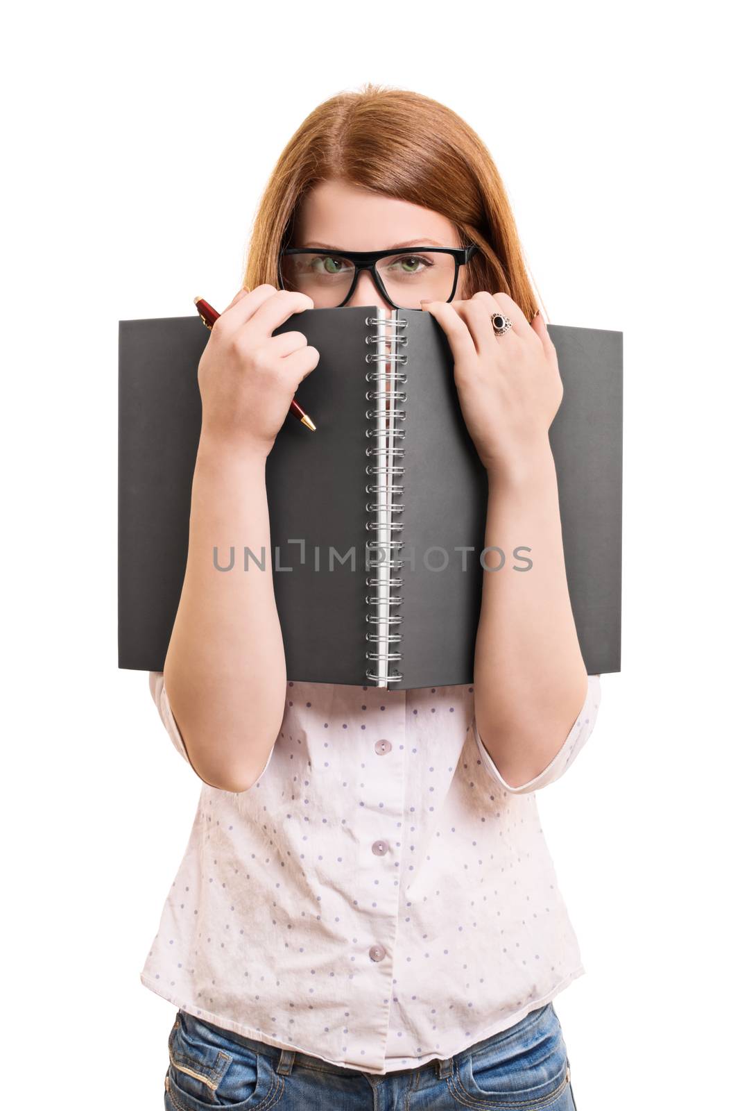 A portrait of a young female student hiding behind her book, isolated on white background.