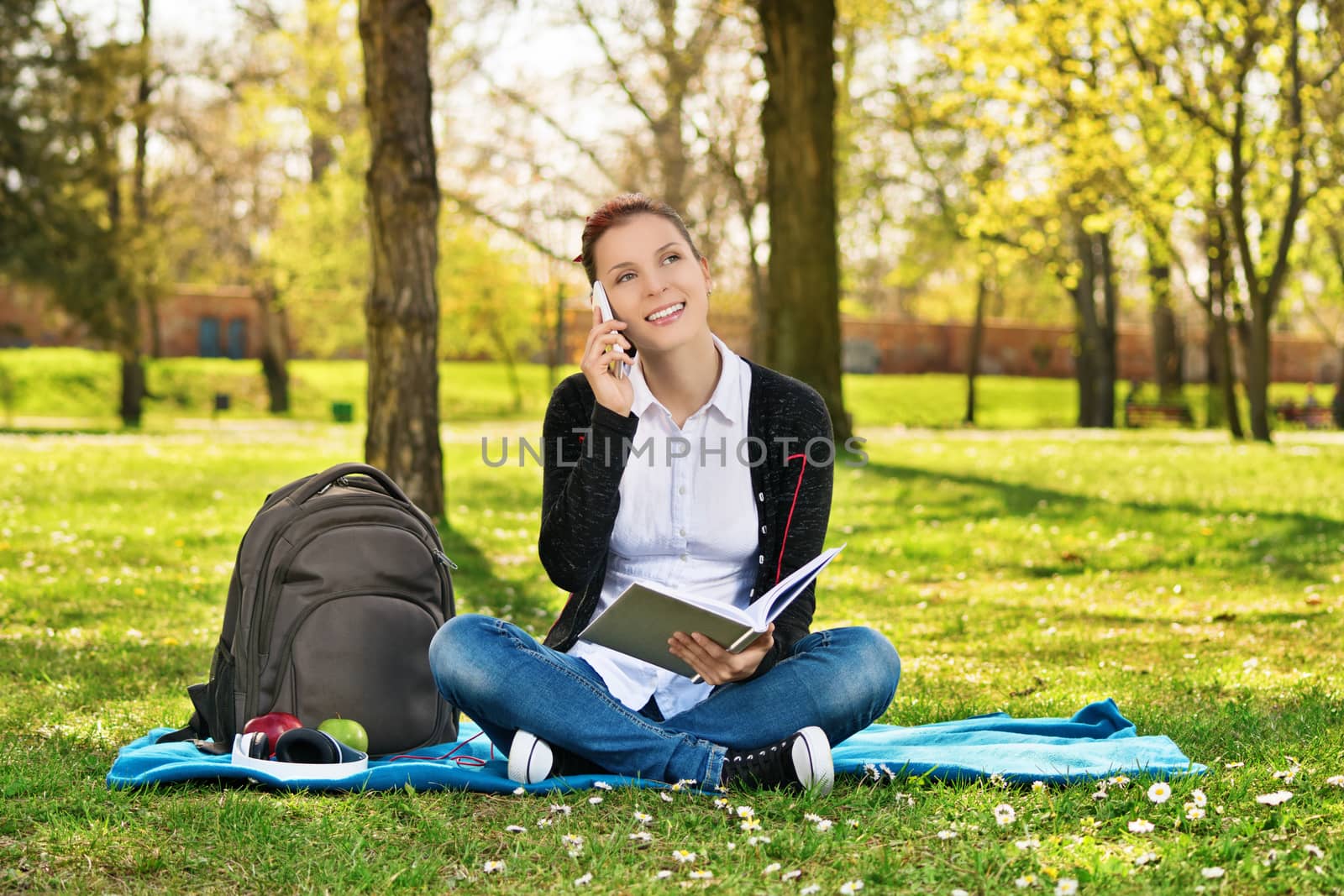 Female student in a park talking on the phone by Mendelex
