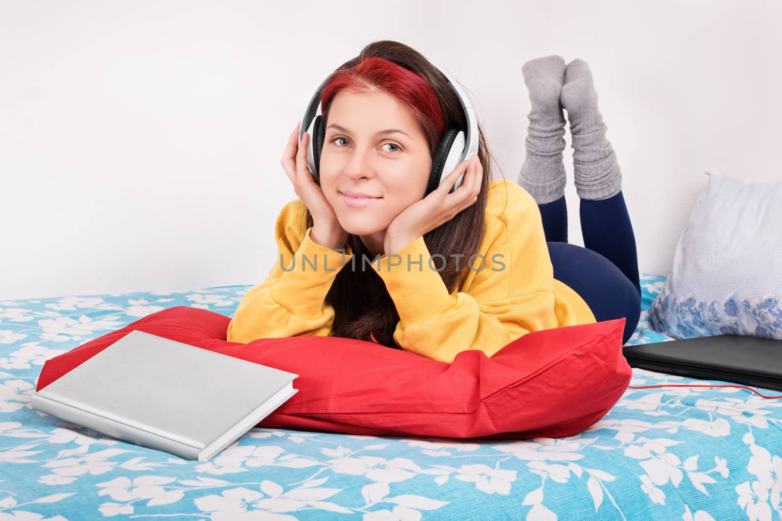Girl in bed with headphones, book and a laptop by Mendelex