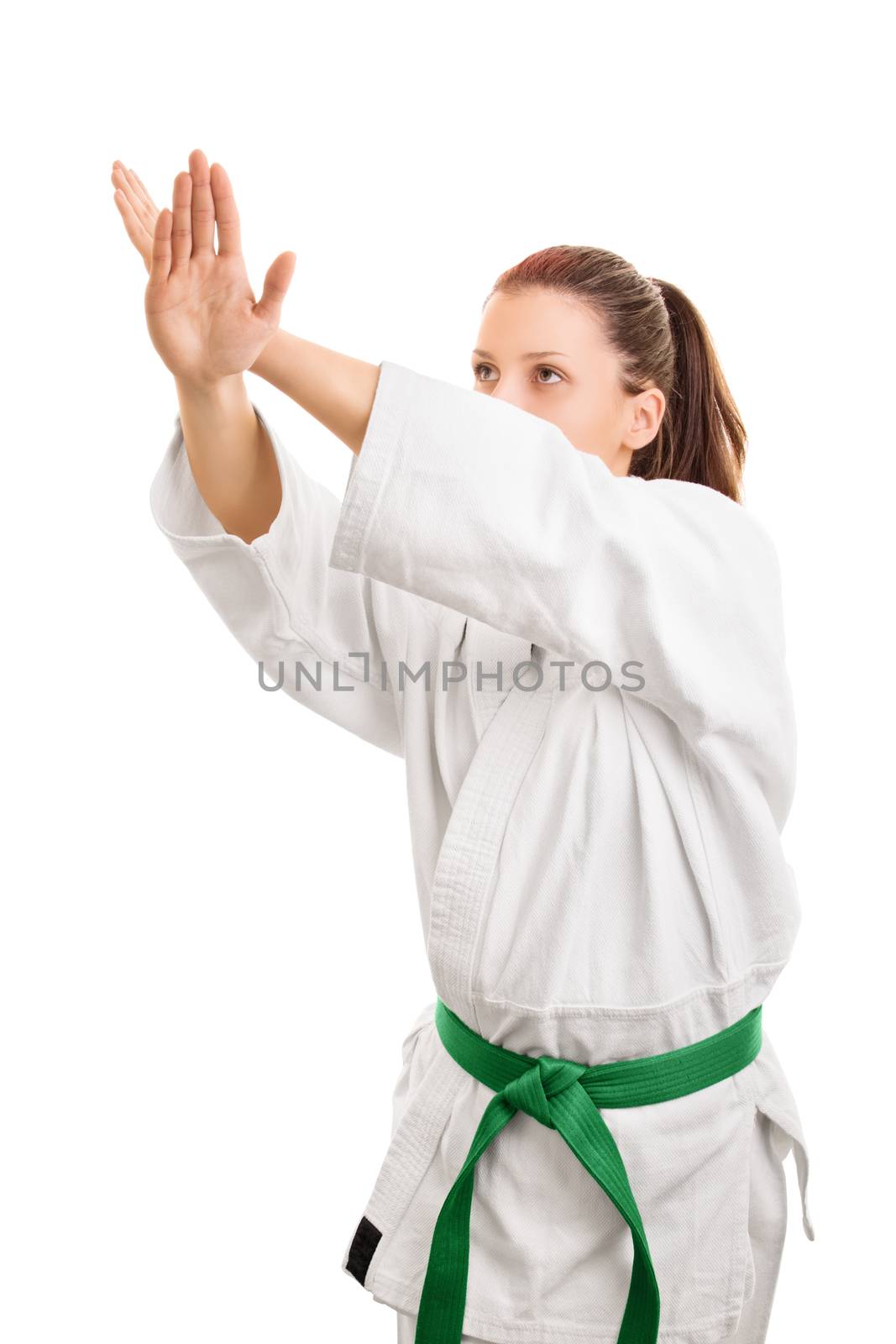 Block this way. Young girl wearing kimono with green belt in block stance, isolated on white background.