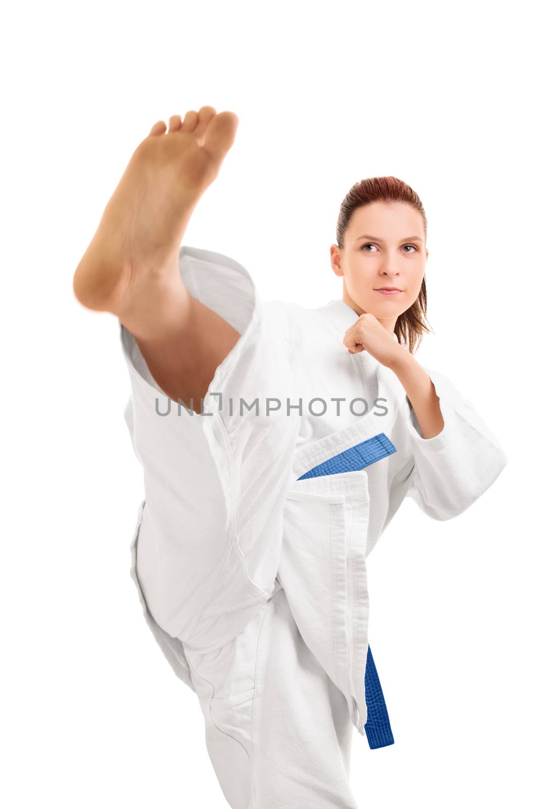A portrait of a beautiful young girl in a kimono with blue belt demonstrating a kick, isolated on white background.