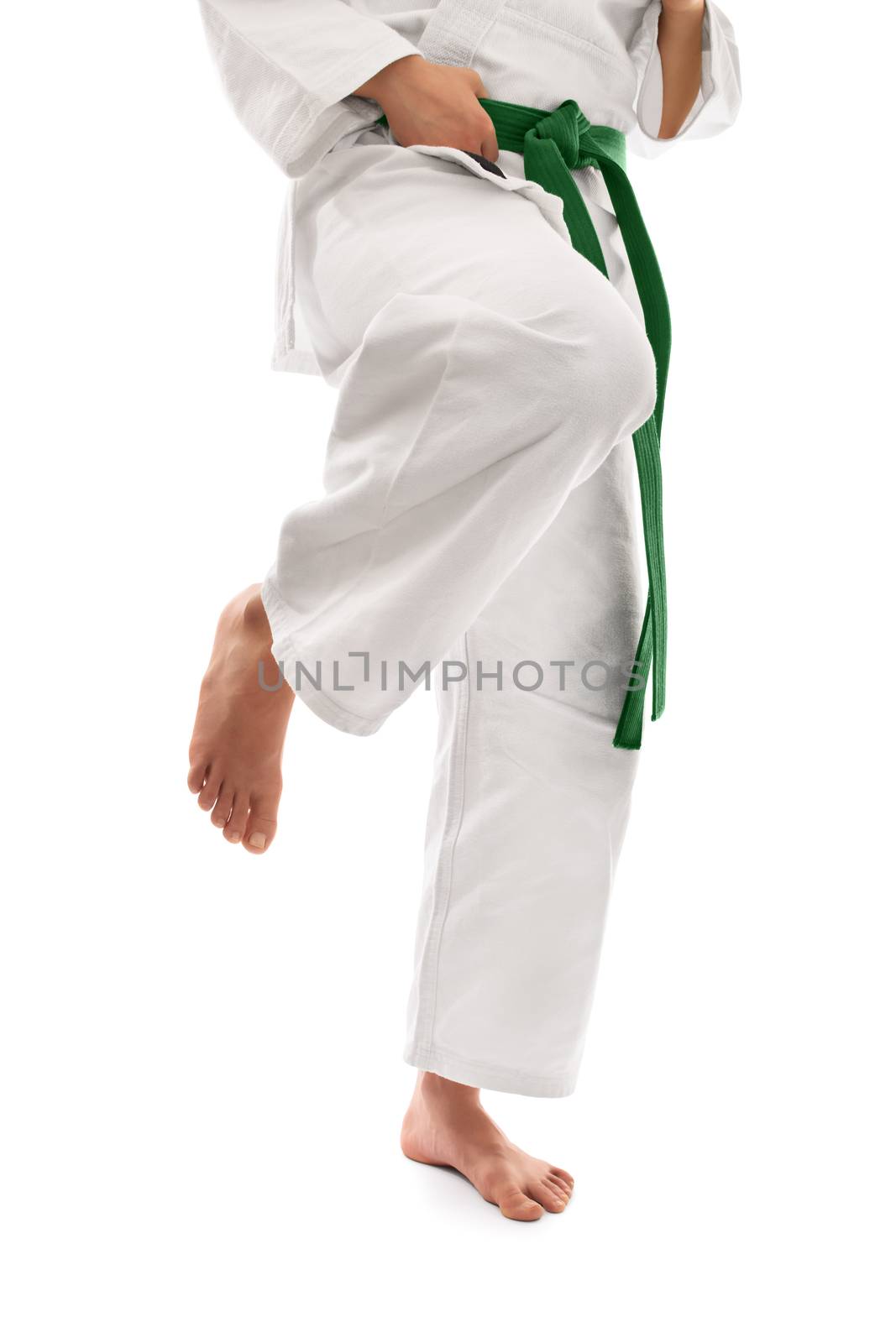 Close up shot of below the waist section of a girl in a kimono with green belt preparing for a knee kick, isolated on white background.