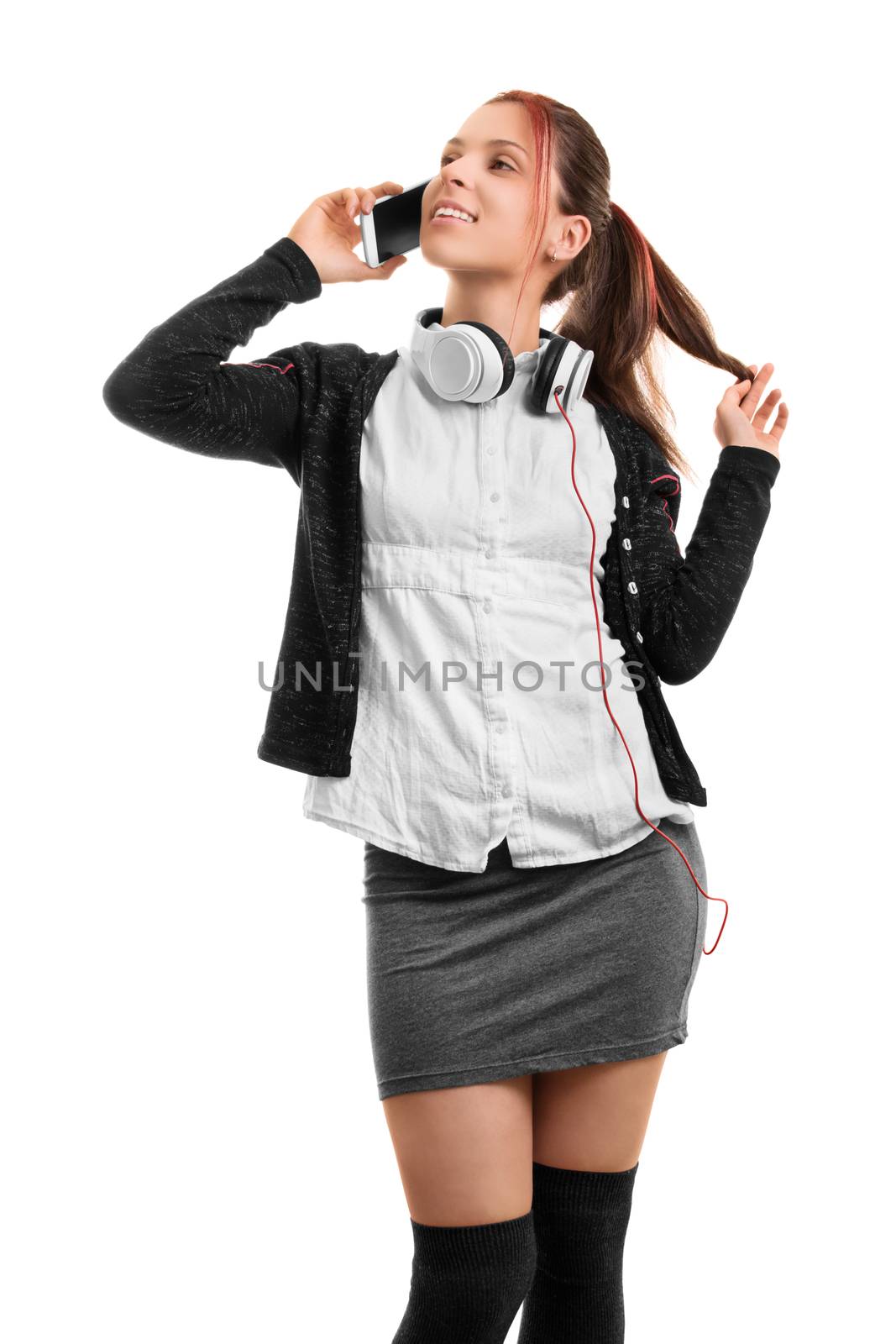 Hey, what's up? Beautiful smiling young girl in school uniform talking on the phone, isolated on white background.